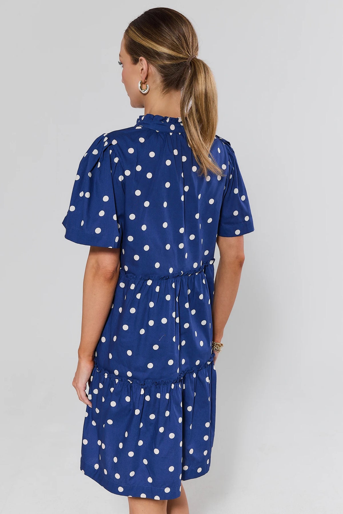 Evan Navy Polka Dot Short Dress - back view showing flutter sleeves, ruffle tiers, and modest coverage | Avara