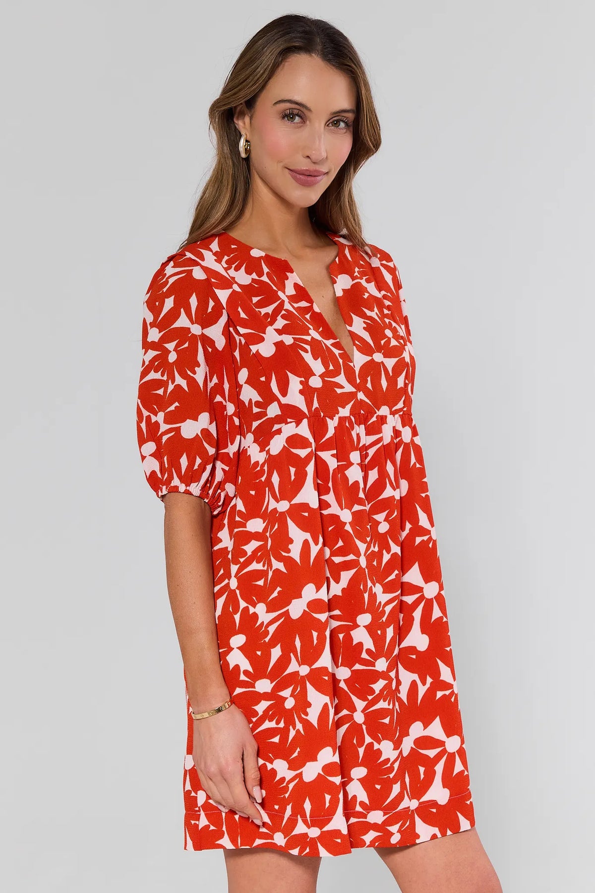 side shot Woman wearing a red and white floral dress on a gray background