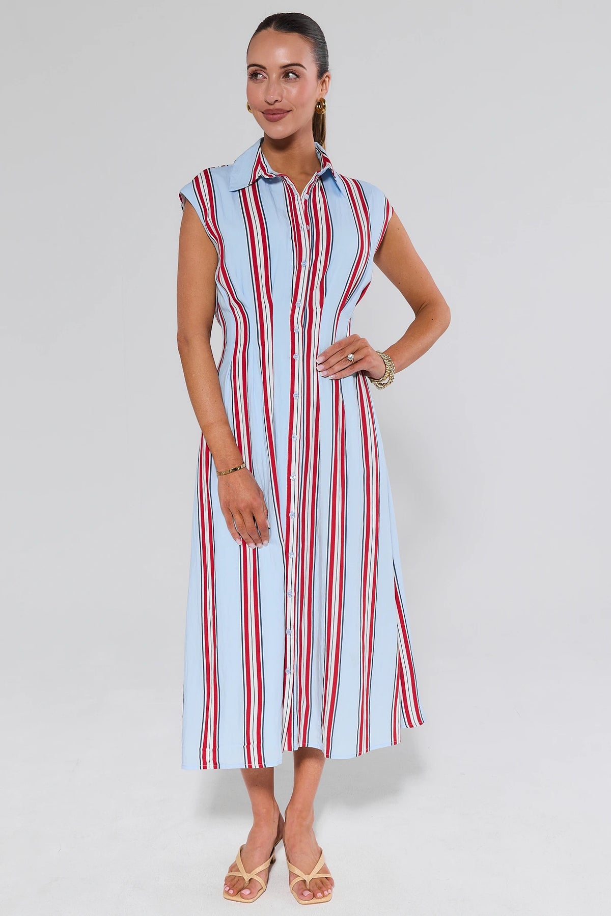 Woman wearing a sleeveless dress with vertical red and blue stripes on a white background