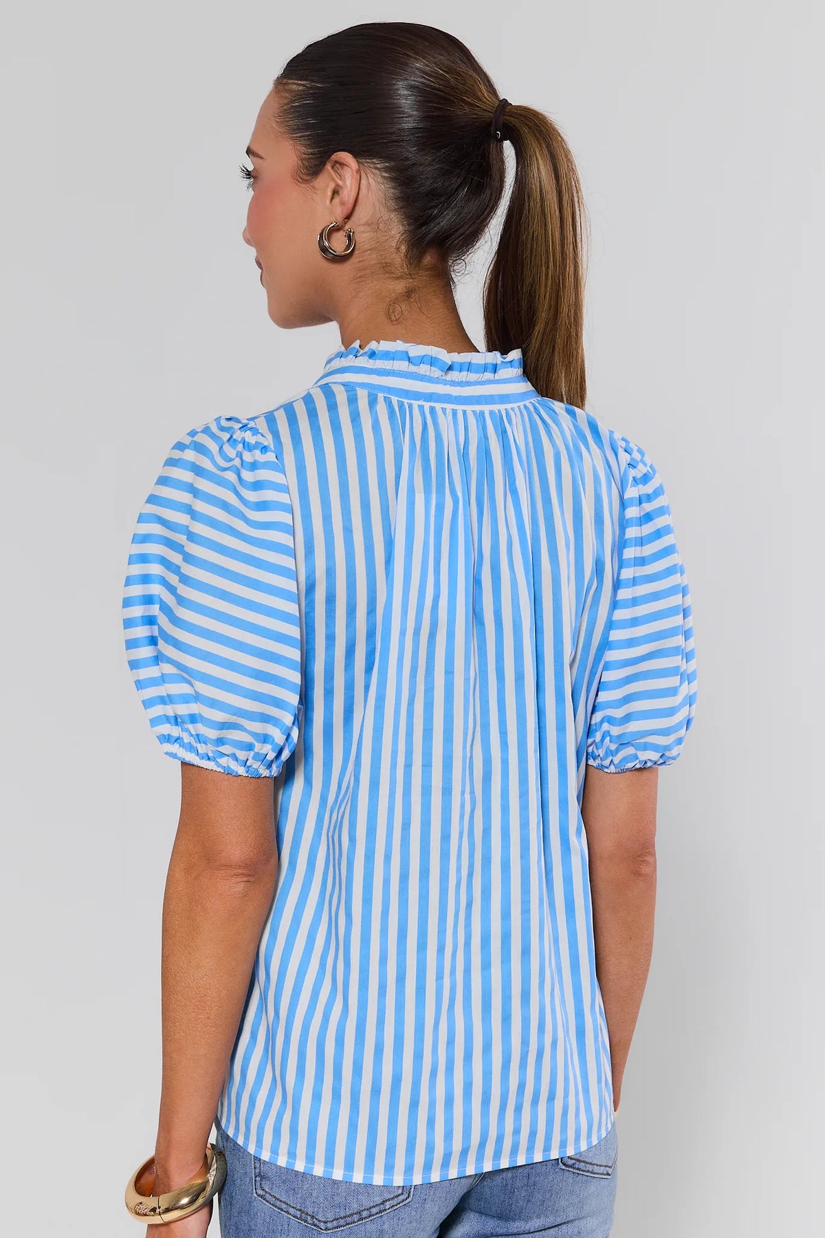 Woman wearing a blue and white striped blouse against a plain background