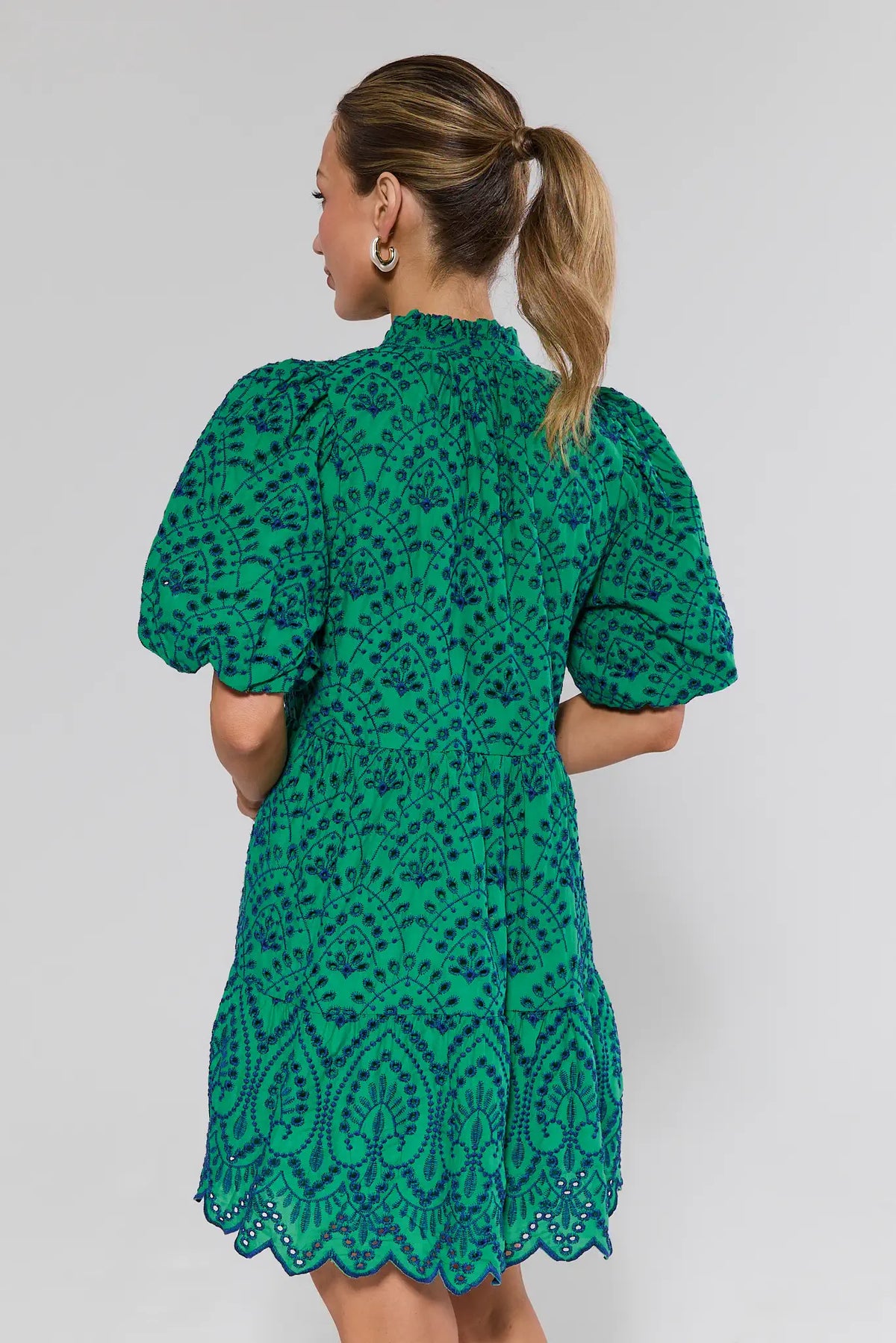 Woman wearing a green patterned dress against a plain background