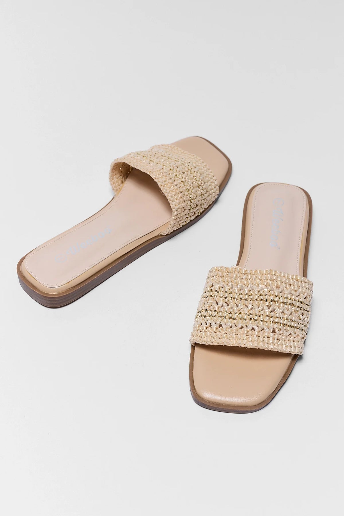 Pair of beige sandals with woven design on a white background
