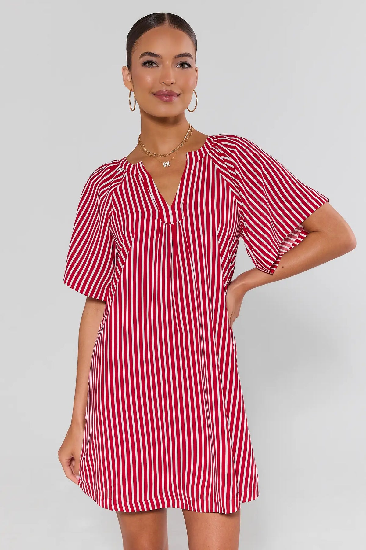 Woman wearing a red and white striped dress on a plain background
