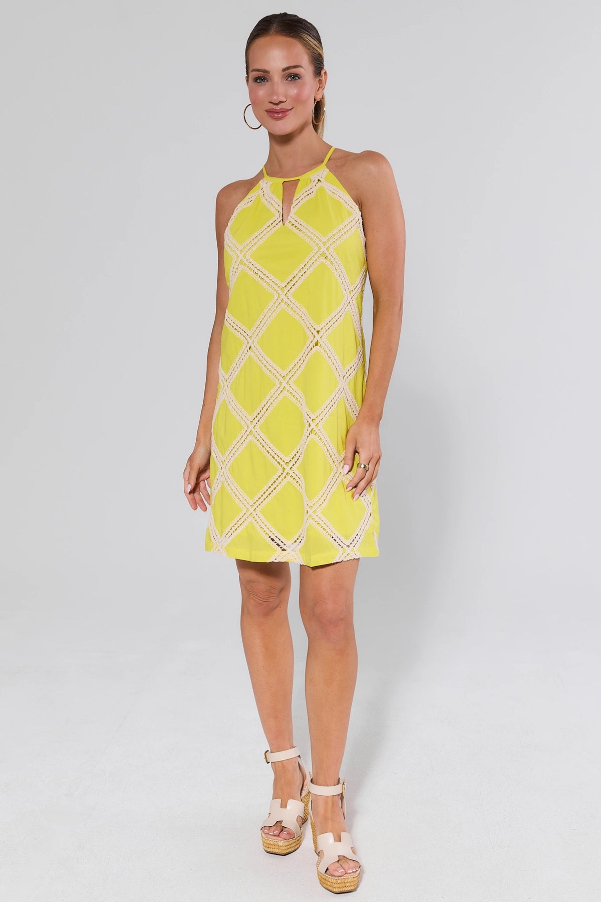 Woman wearing a yellow patterned dress and heels on a white background