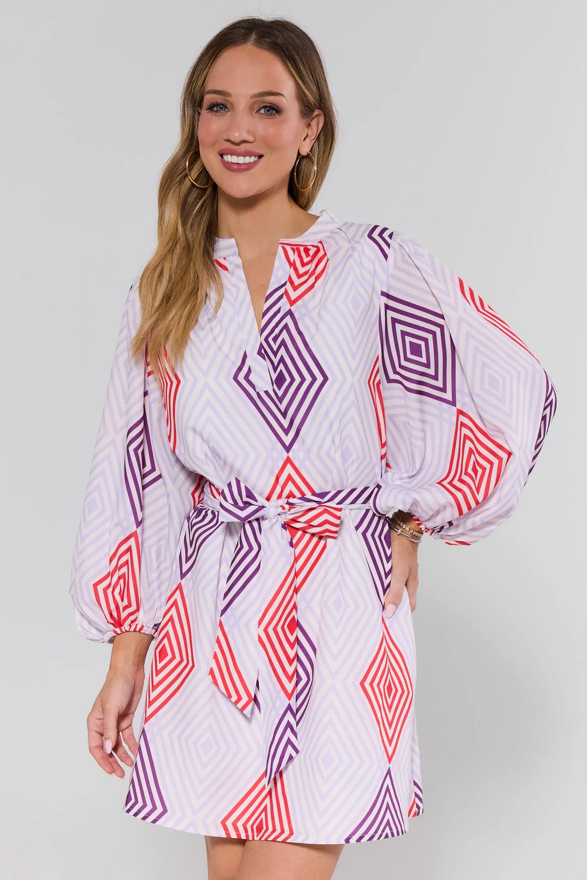 Woman wearing a patterned dress with geometric design on a plain background