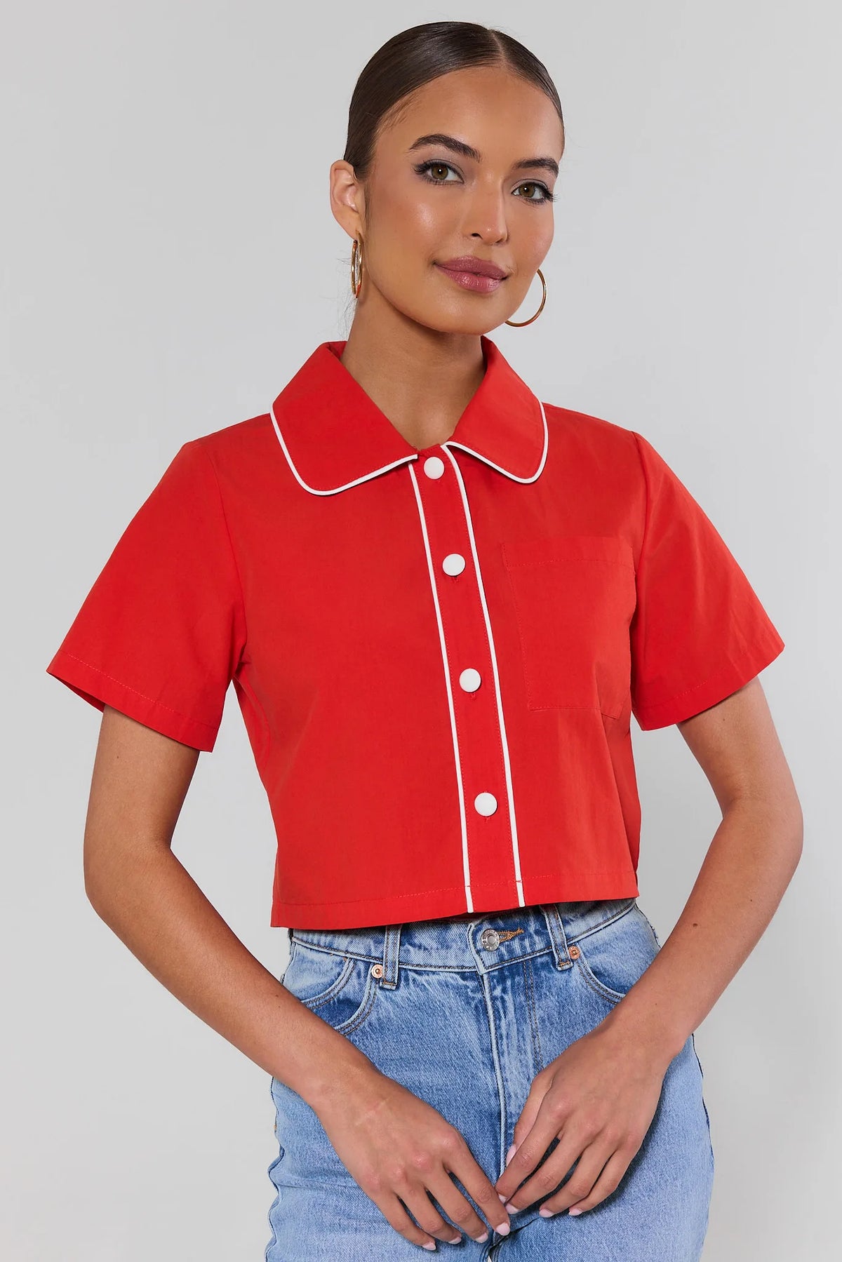 Belle Red Contrast Trim Top with white piping and button front, styled with light wash jeans, angled front view | Avara