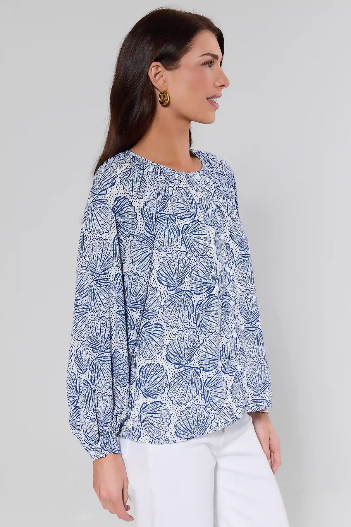 Side view of blue shell print top with balloon long sleeves and relaxed fit, styled with white pants | Avara