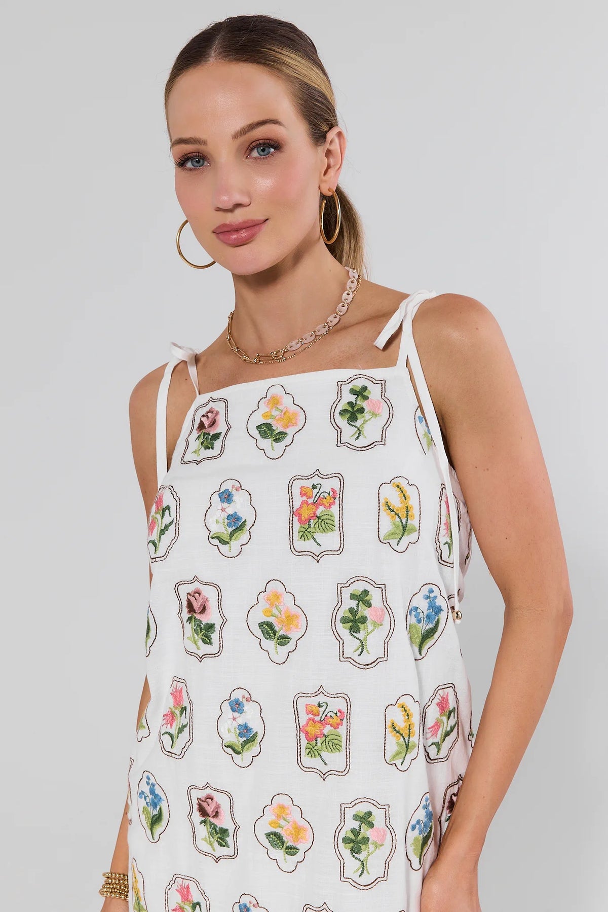 Woman wearing a white dress with floral patterns on a plain background