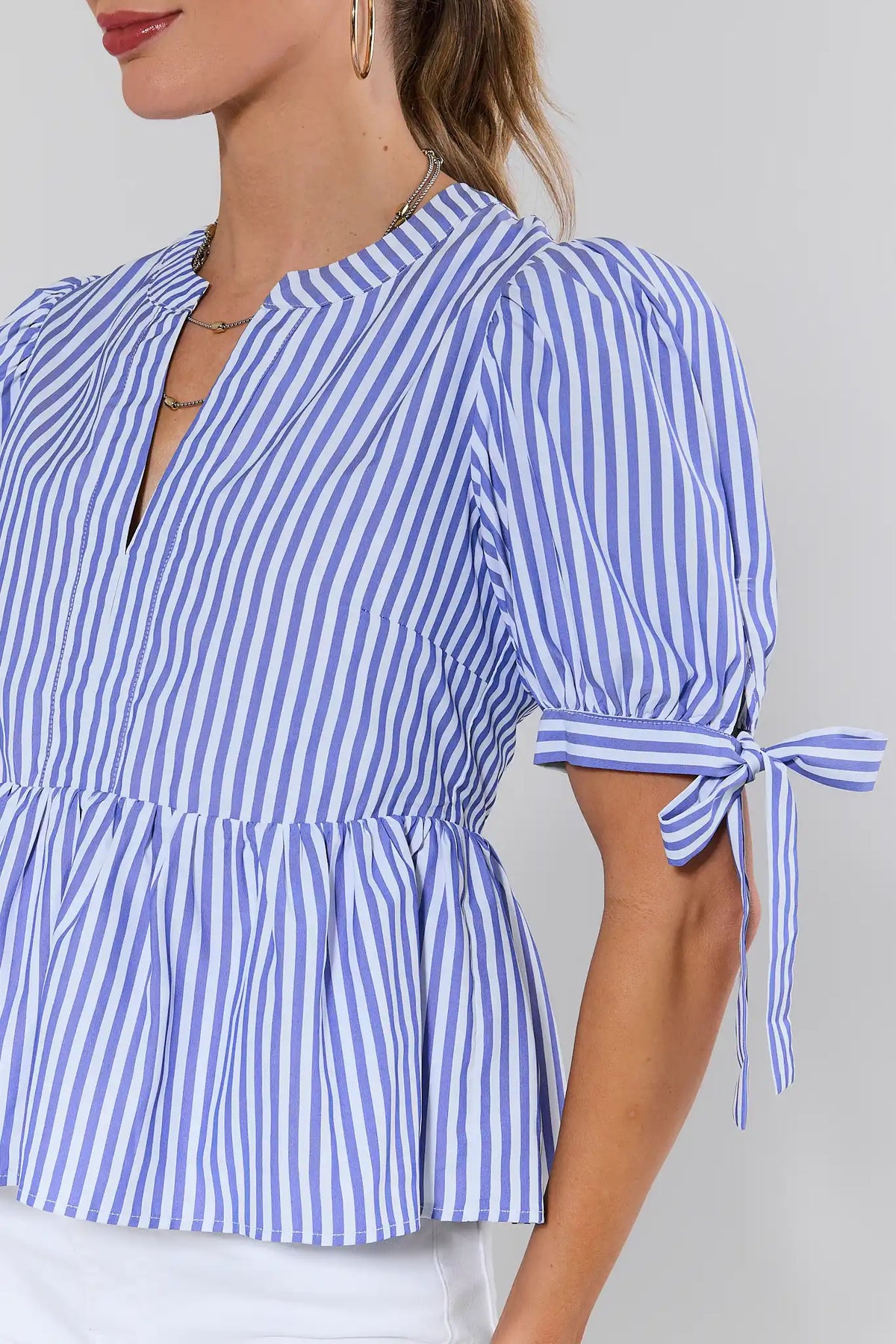 Blue and white striped peplum blouse with tied sleeve cuffs and flared hem - Close-Up Detail | Avara