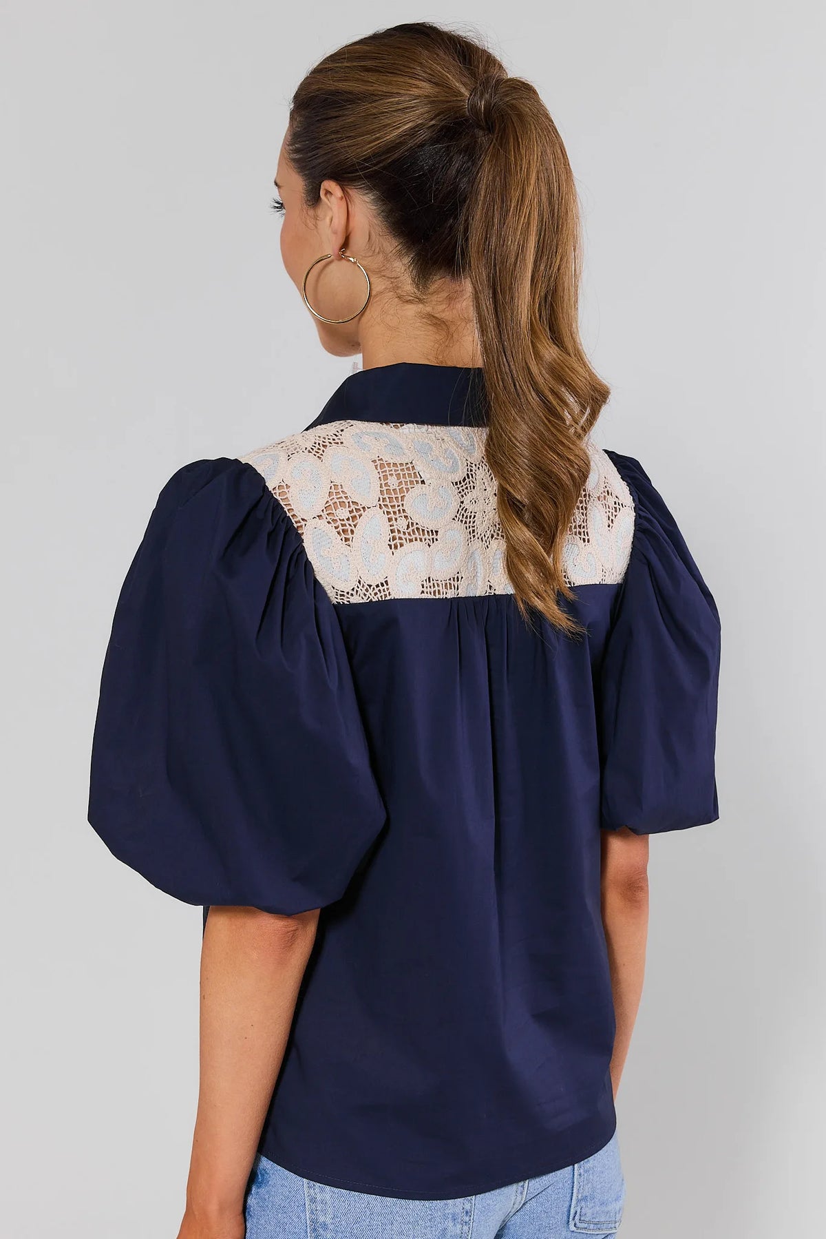 Navy blue crochet lace top back view showing cream lace yoke panel and statement puff sleeves on model | Avara