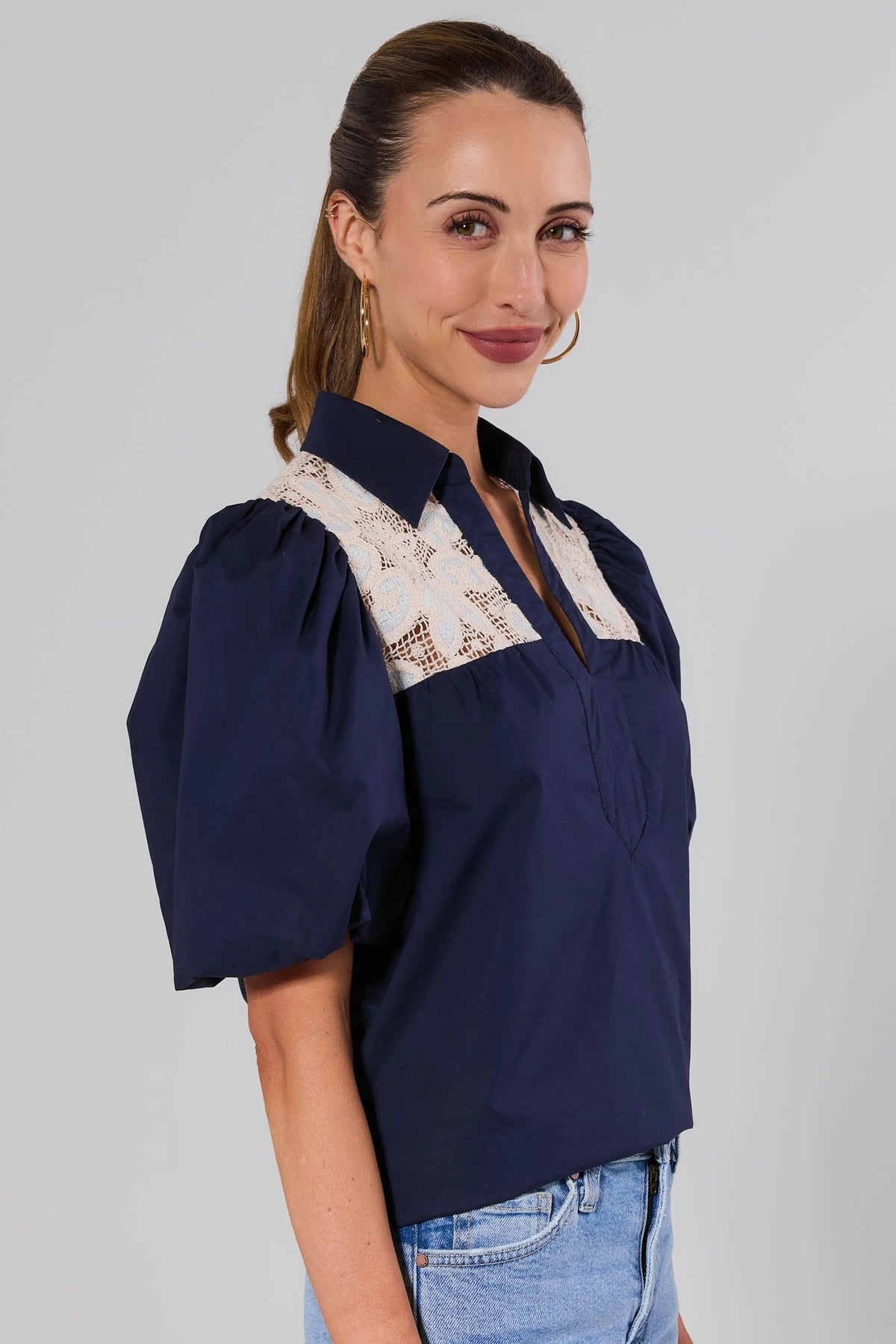 Navy crochet top with puff sleeves, three-quarter side view showing cream lace yoke and collar detail | Avara
