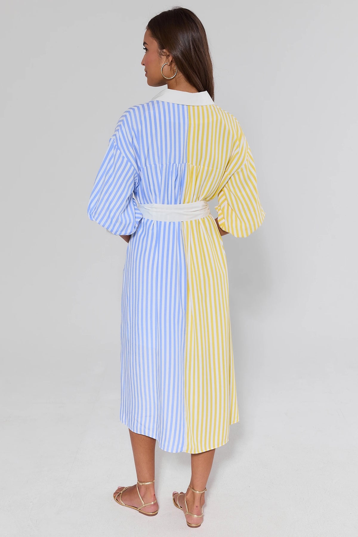Two-toned striped midi dress in blue and yellow with white belt, back view on model | Avara
