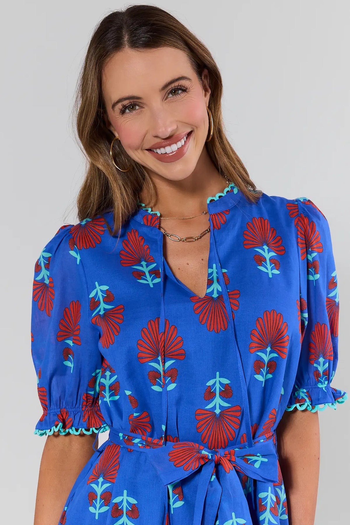 close up Woman wearing a blue dress with red and green floral patterns on a plain background