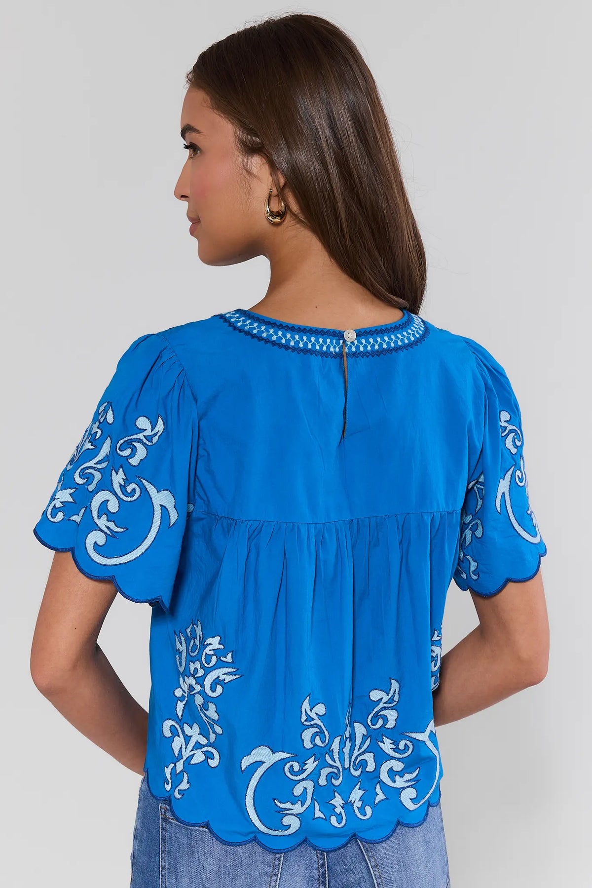 Blue embroidered scalloped hem blouse showing back button closure and flutter sleeves | Avara