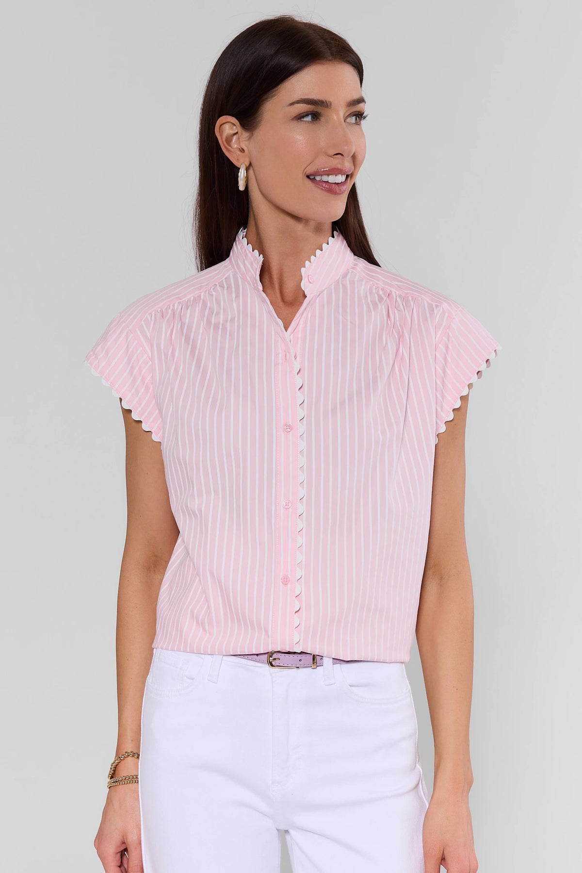 Woman wearing a light pink blouse with ruffled sleeves on a plain background