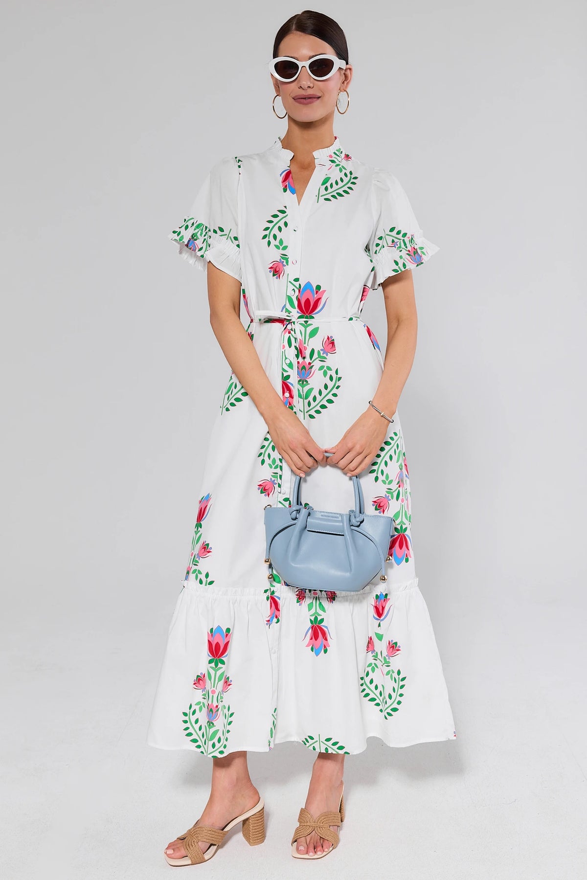 White Floral Printed Maxi Dress full-length front view, flutter sleeves, belted waist, styled with blue bag | Avara