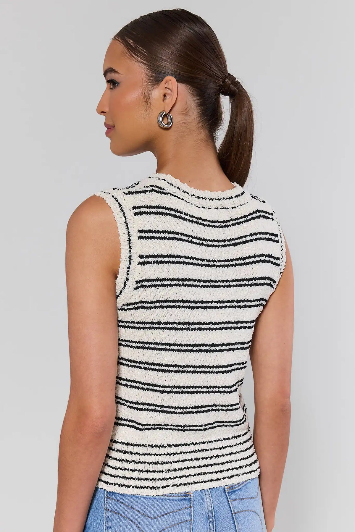 Woman wearing white and black striped knit tank top with jeans - Back View | Avara