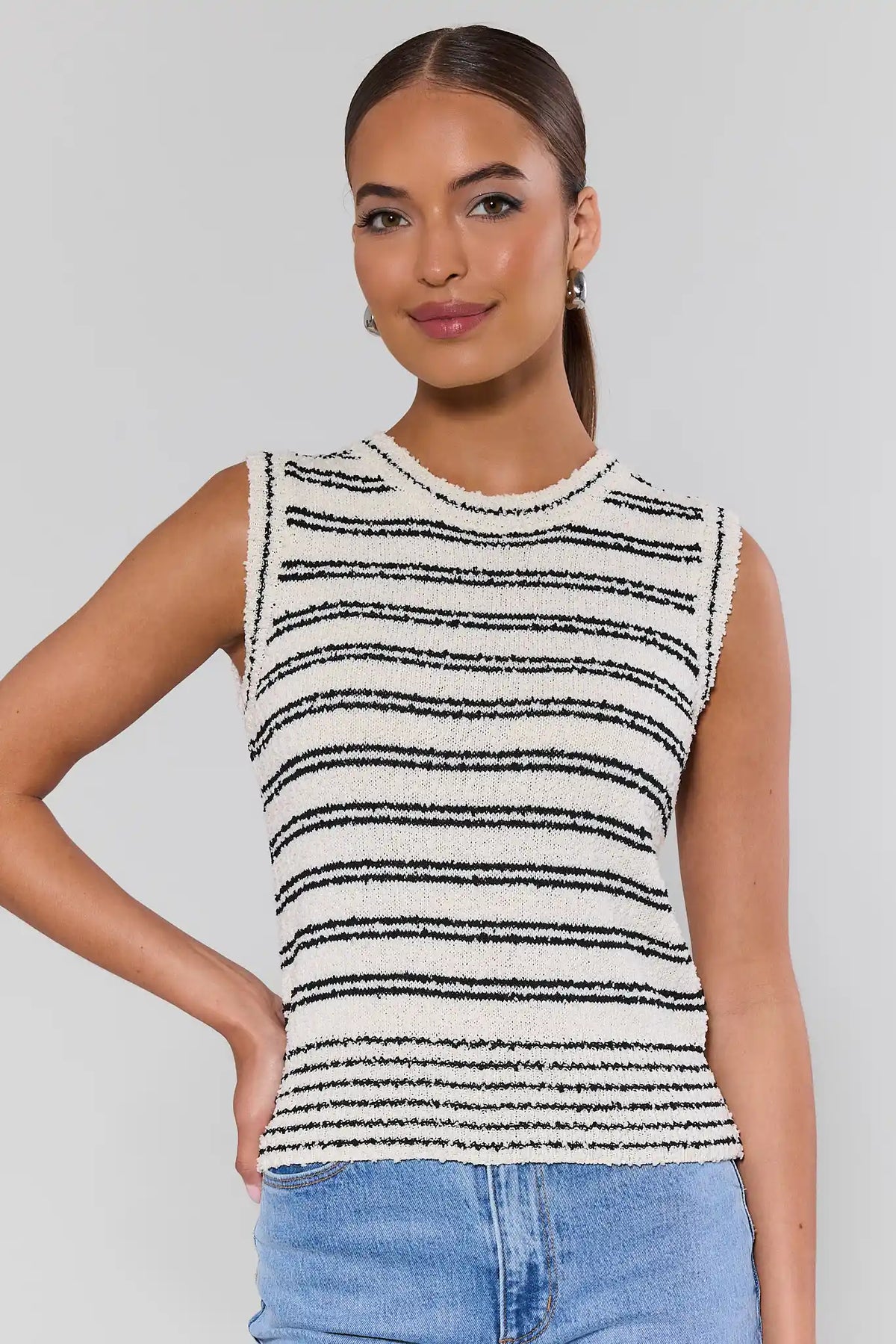 Woman wearing a white black striped knit tank top with crew neckline and jeans - Front View | Avara