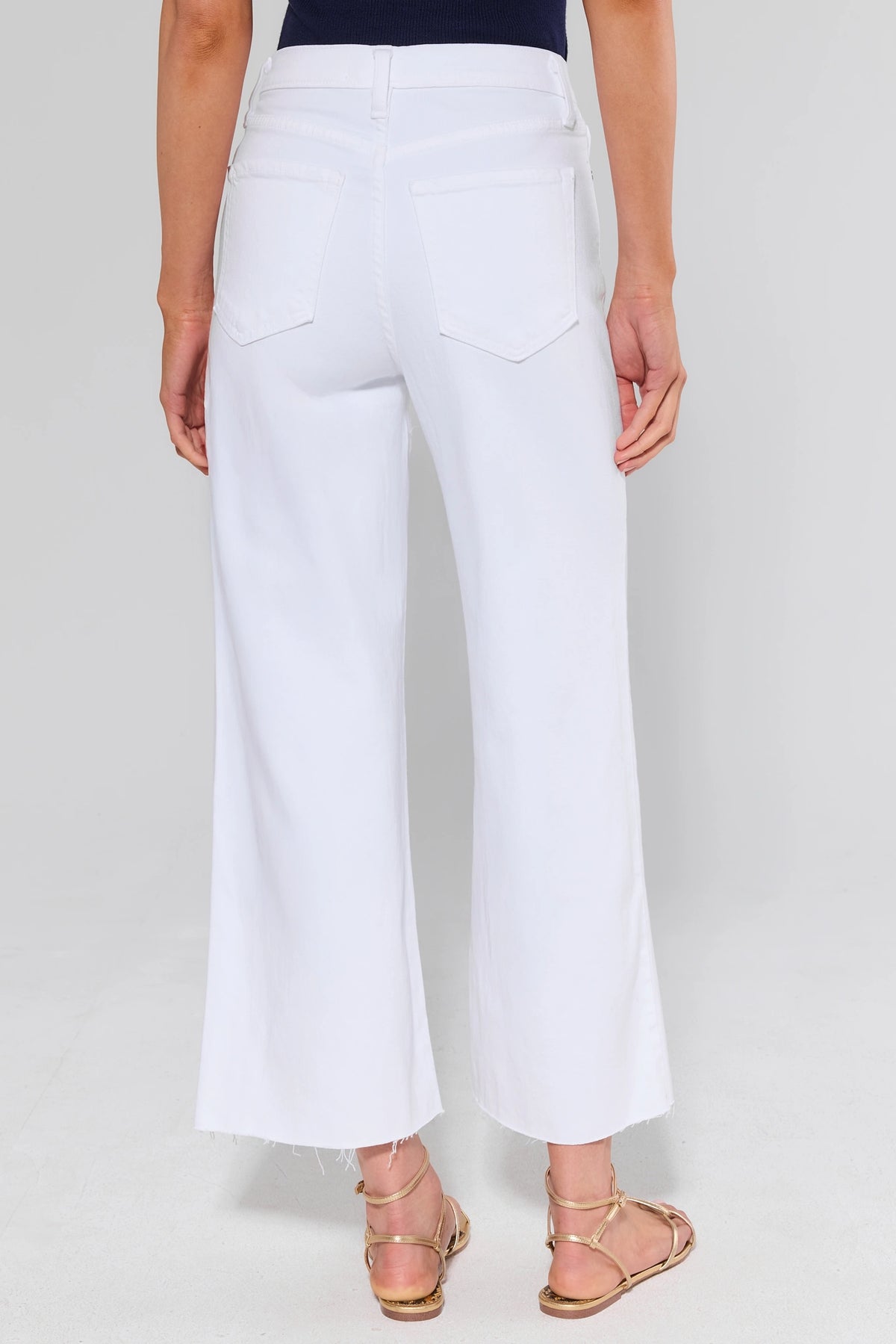 White wide leg jeans back view showing five-pocket design, high rise waist, and raw hem detail | Avara