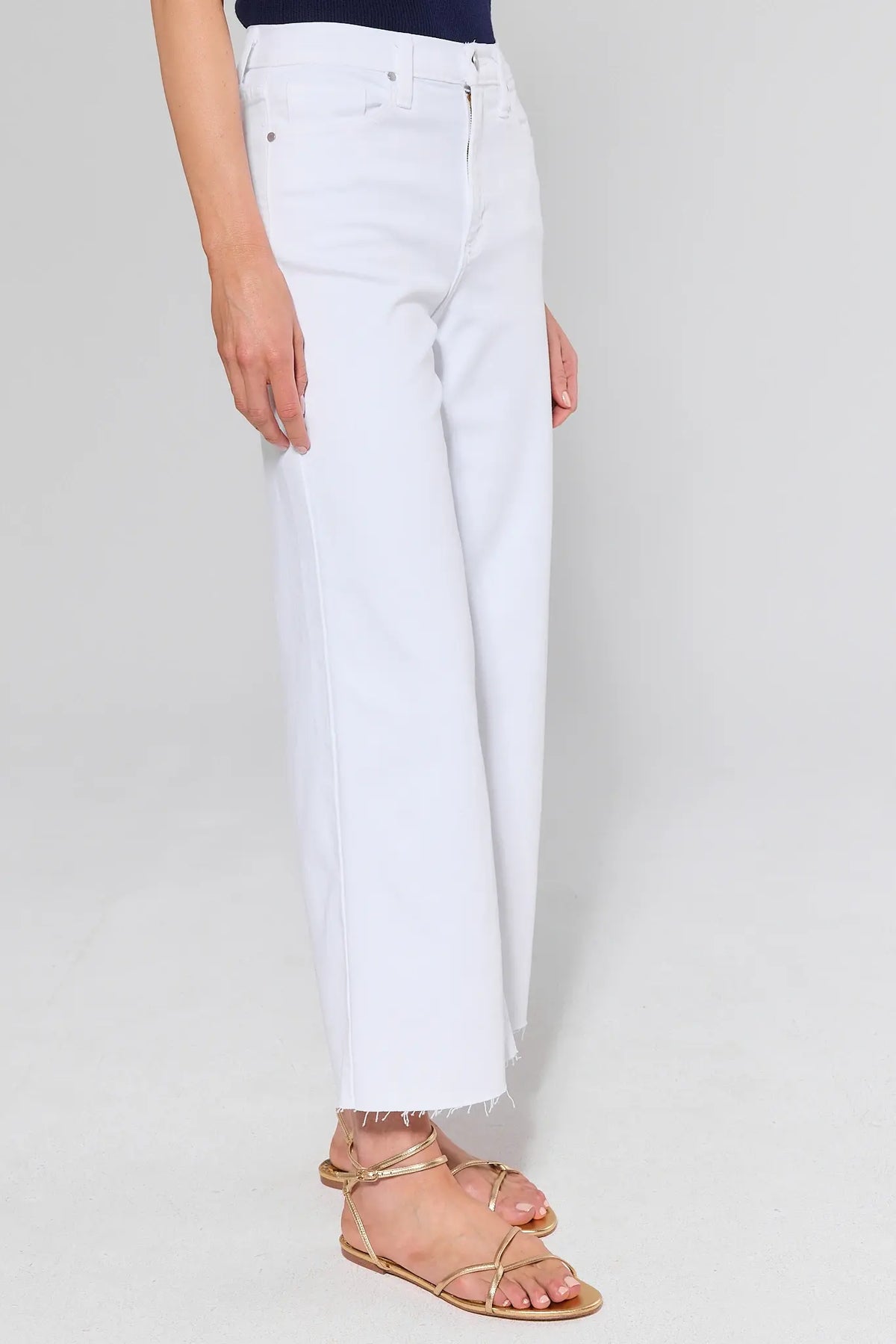 White wide leg jeans side view showing high rise fit, raw frayed hem, and relaxed wide leg silhouette | Avara
