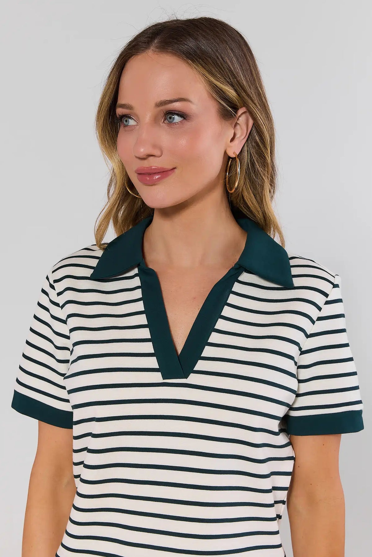 Close-up of green striped polo top with V-neck collar and contrast green trim detail | Avara