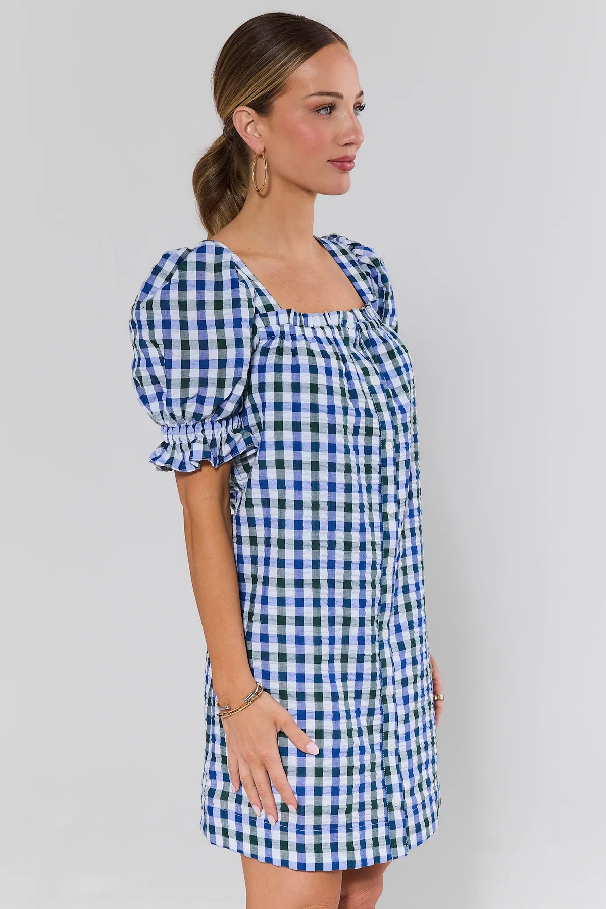 Side view of navy blue gingham puff sleeve short dress showing ruched texture and hem length | Avara