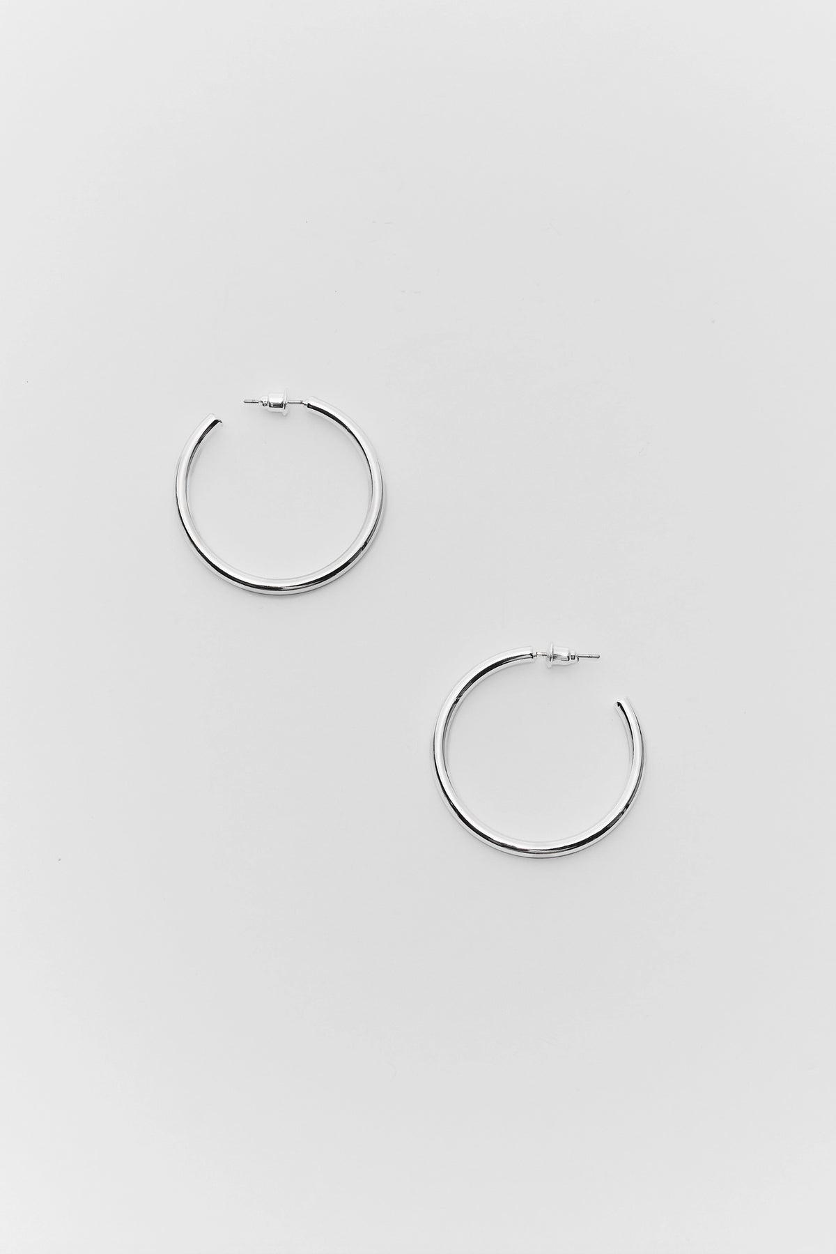 Pair of silver small hoop earrings with push-back closure - Flat Lay | Avara