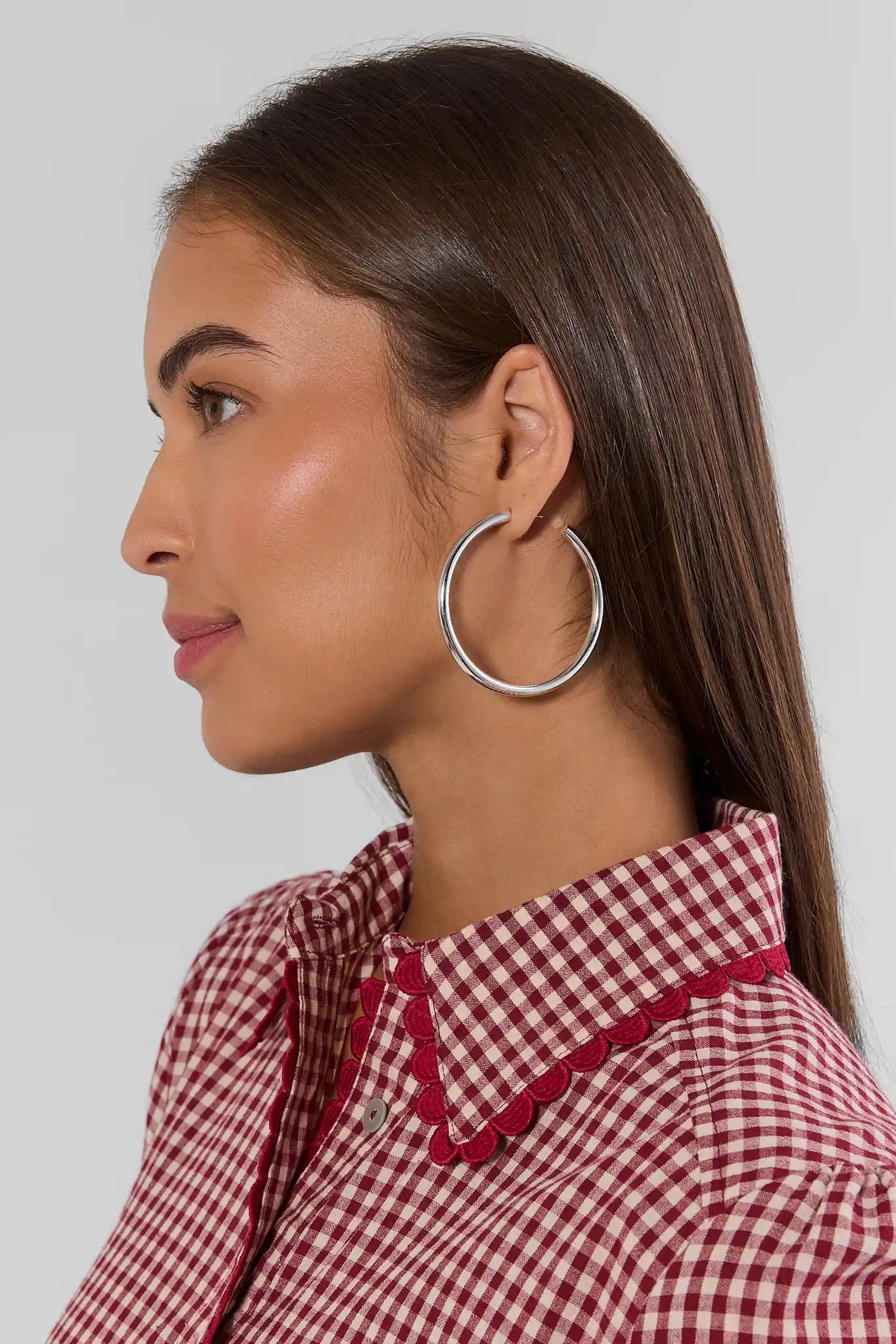 Emily Silver Medium Hoop Earring on model in side profile wearing red gingham top | Avara