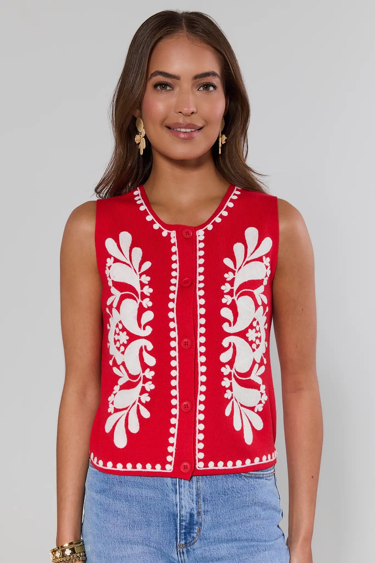 Woman wearing a red sleeveless top with white patterns on a plain background