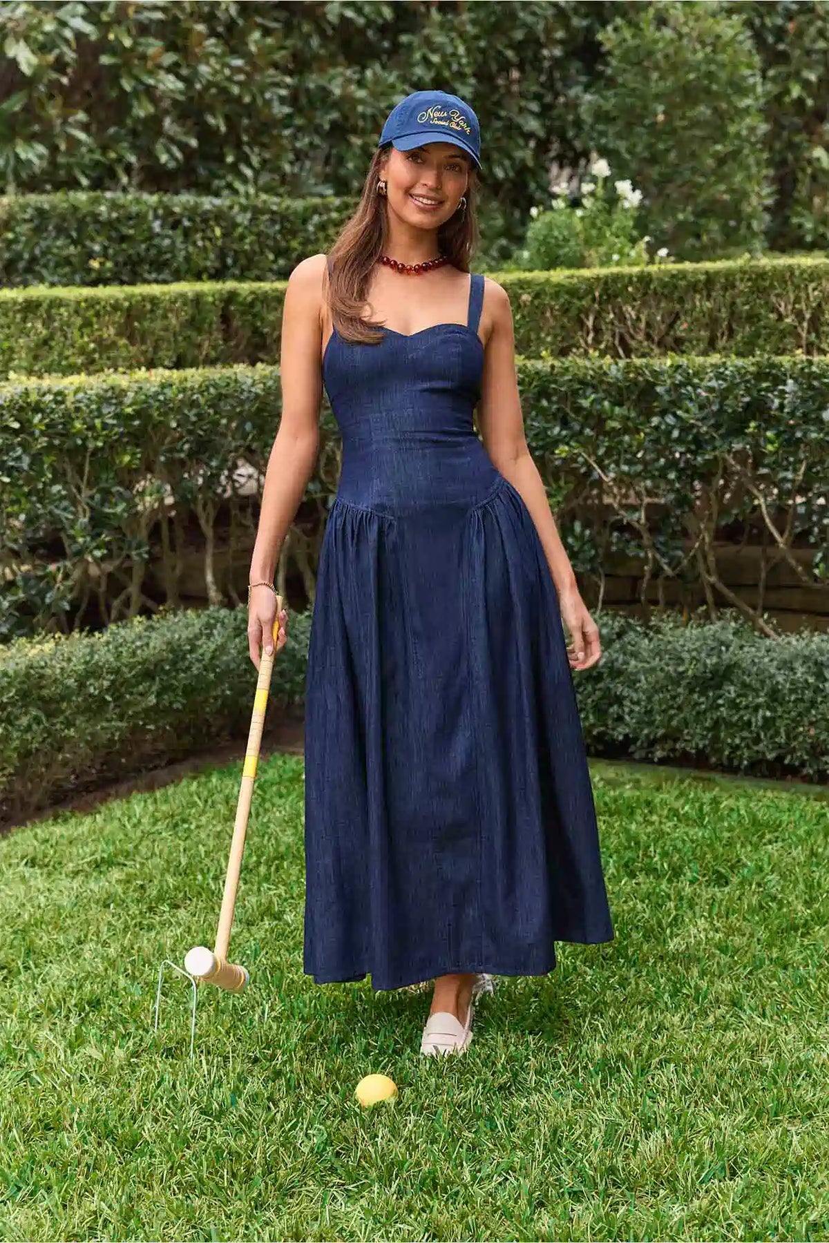 Navy women's denim maxi dress styled outdoors for garden party - Lifestyle Shot with croquet mallet | Avara