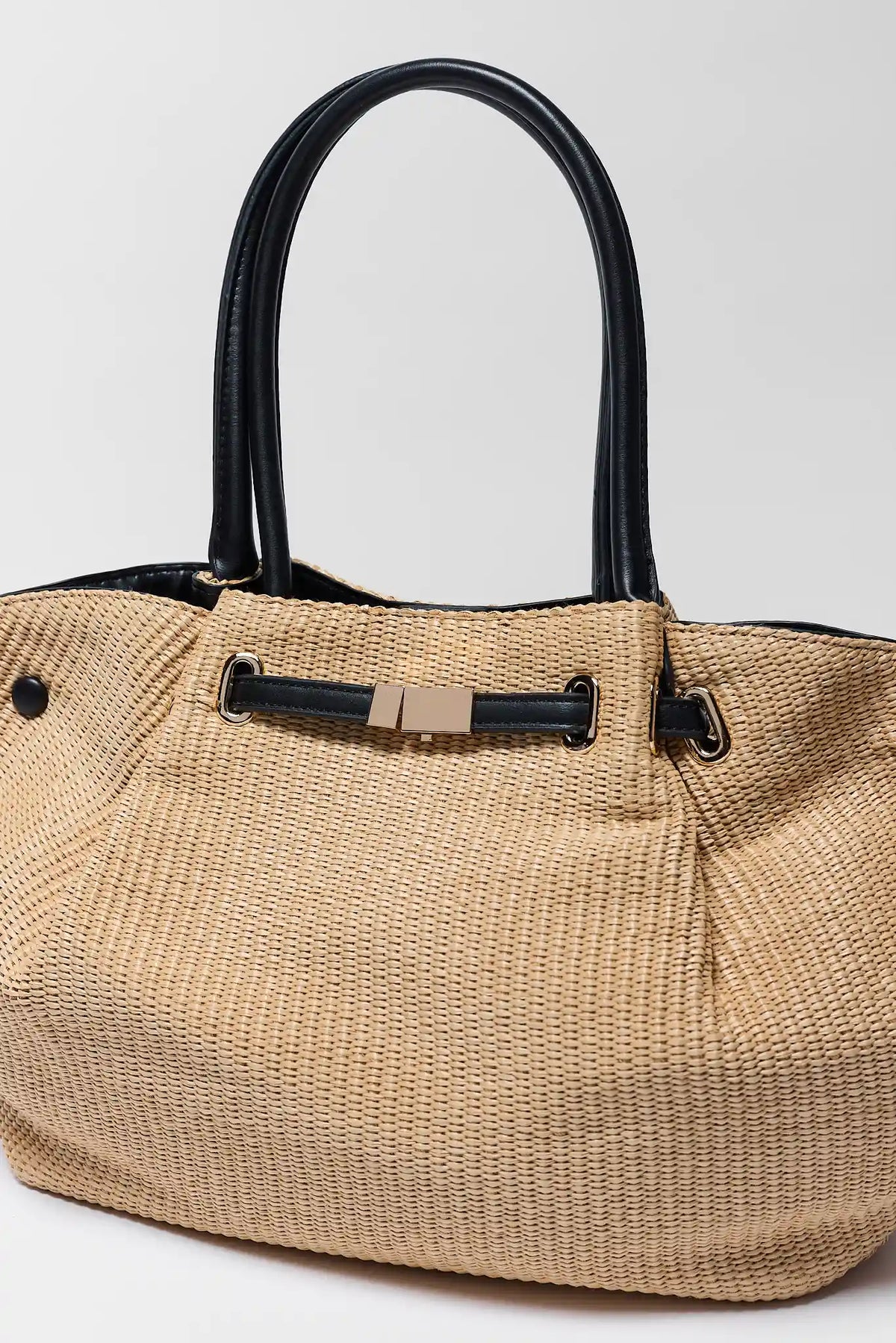 Tan woven straw tote close-up showing gold-tone buckle and black leather trim - Hardware Detail | Avara