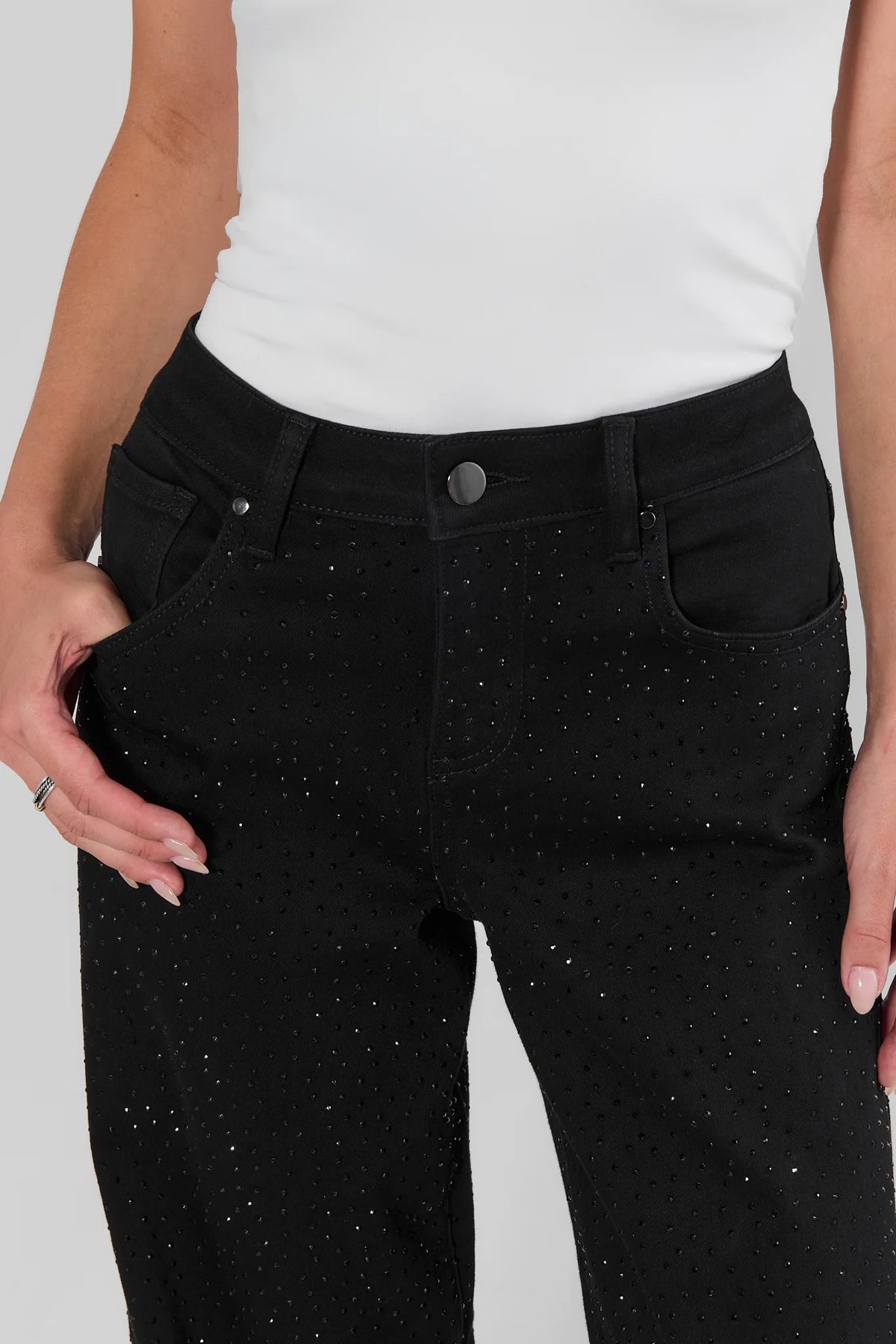 Black rhinestone wide leg jeans front waist close-up on model showing crystal detail and button closure | Avara