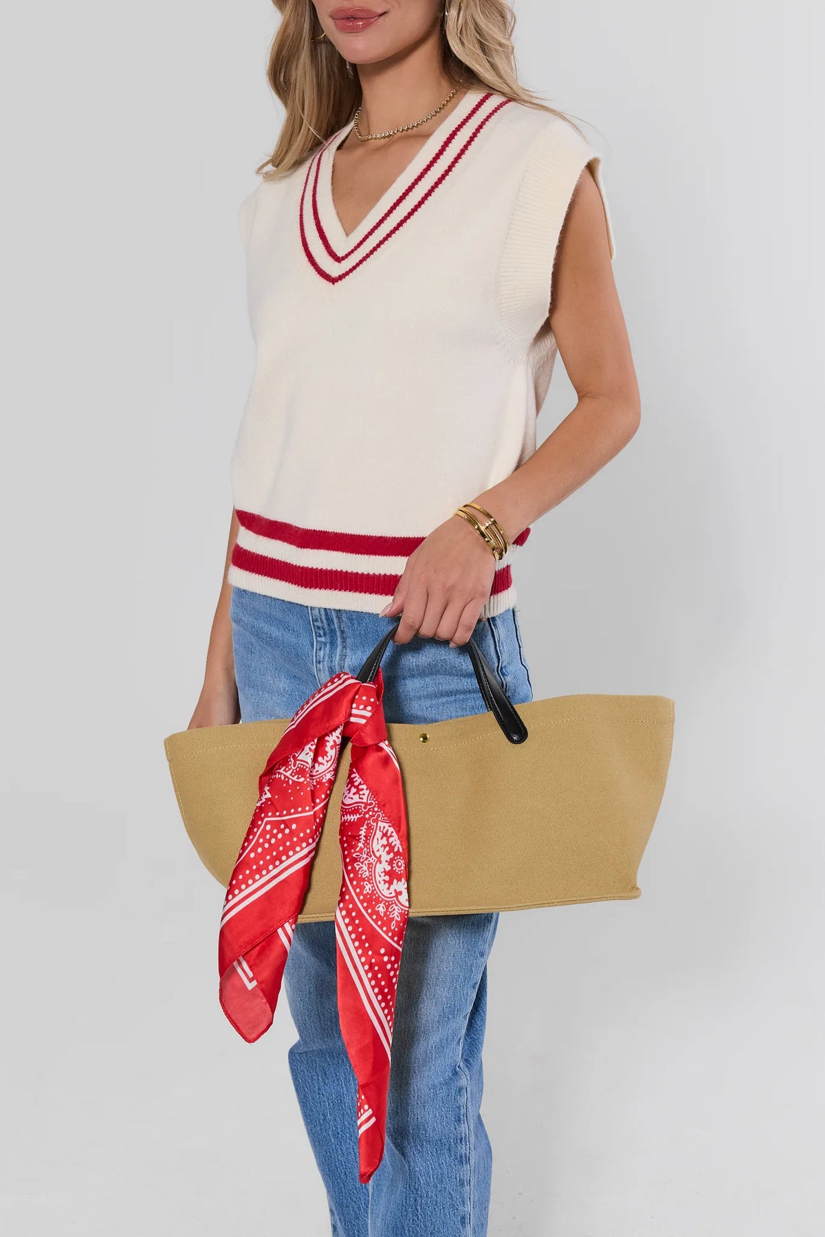 Red paisley scarf tied on tan tote bag, styled with cream knit sweater vest and blue jeans - On Model | Avara