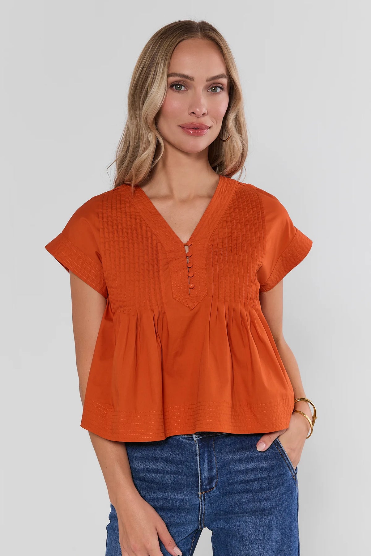 Orange Pleated Button Up Top with V-neck and pintuck detail, styled with blue jeans - Front View | Avara