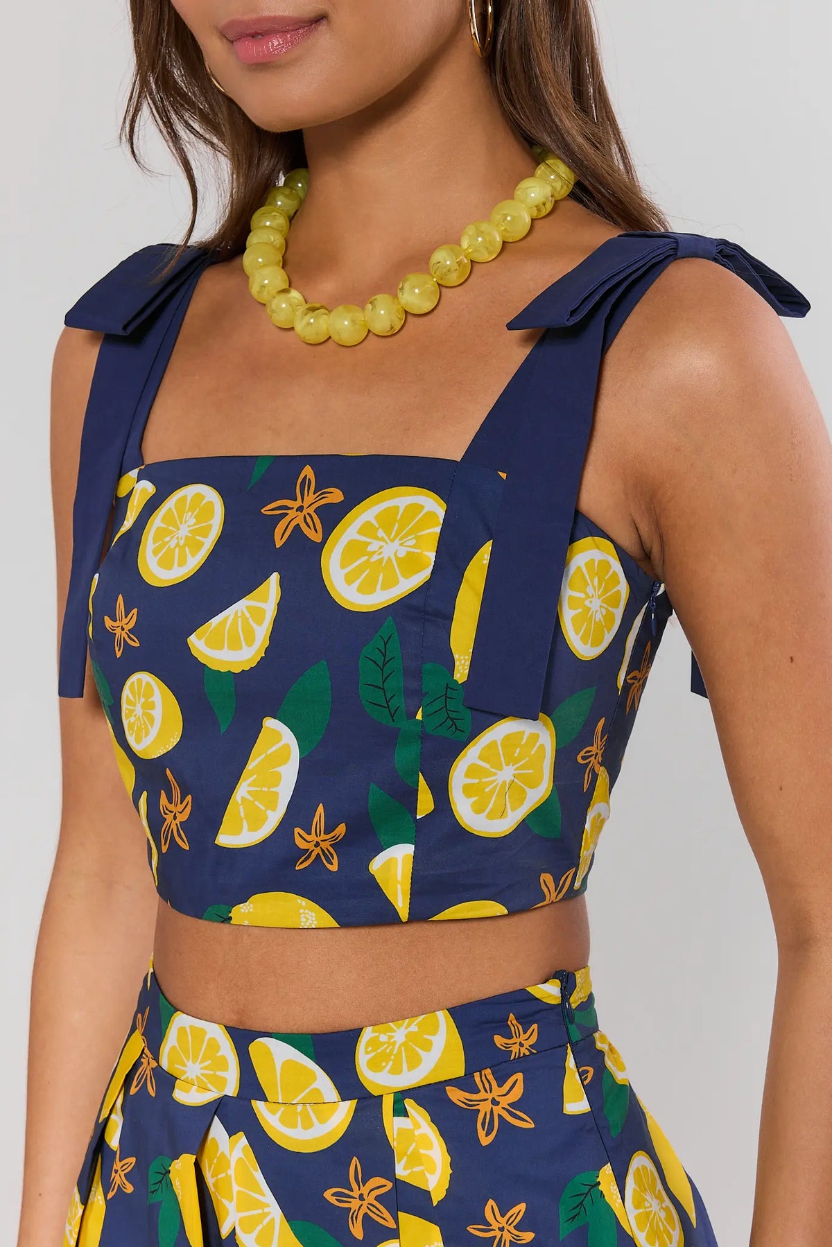 Navy lemon print crop tank top close-up showing square neckline and tie strap detail | Avara