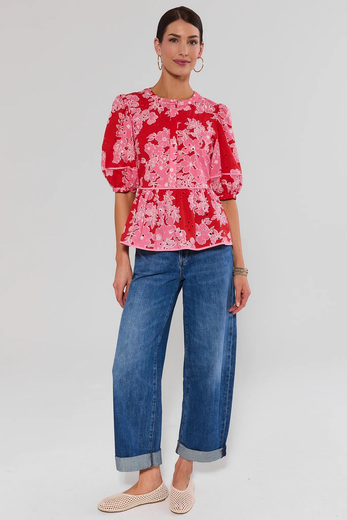 Woman wearing red floral eyelet peplum top styled with wide-leg blue jeans and flats, full-length view | Avara