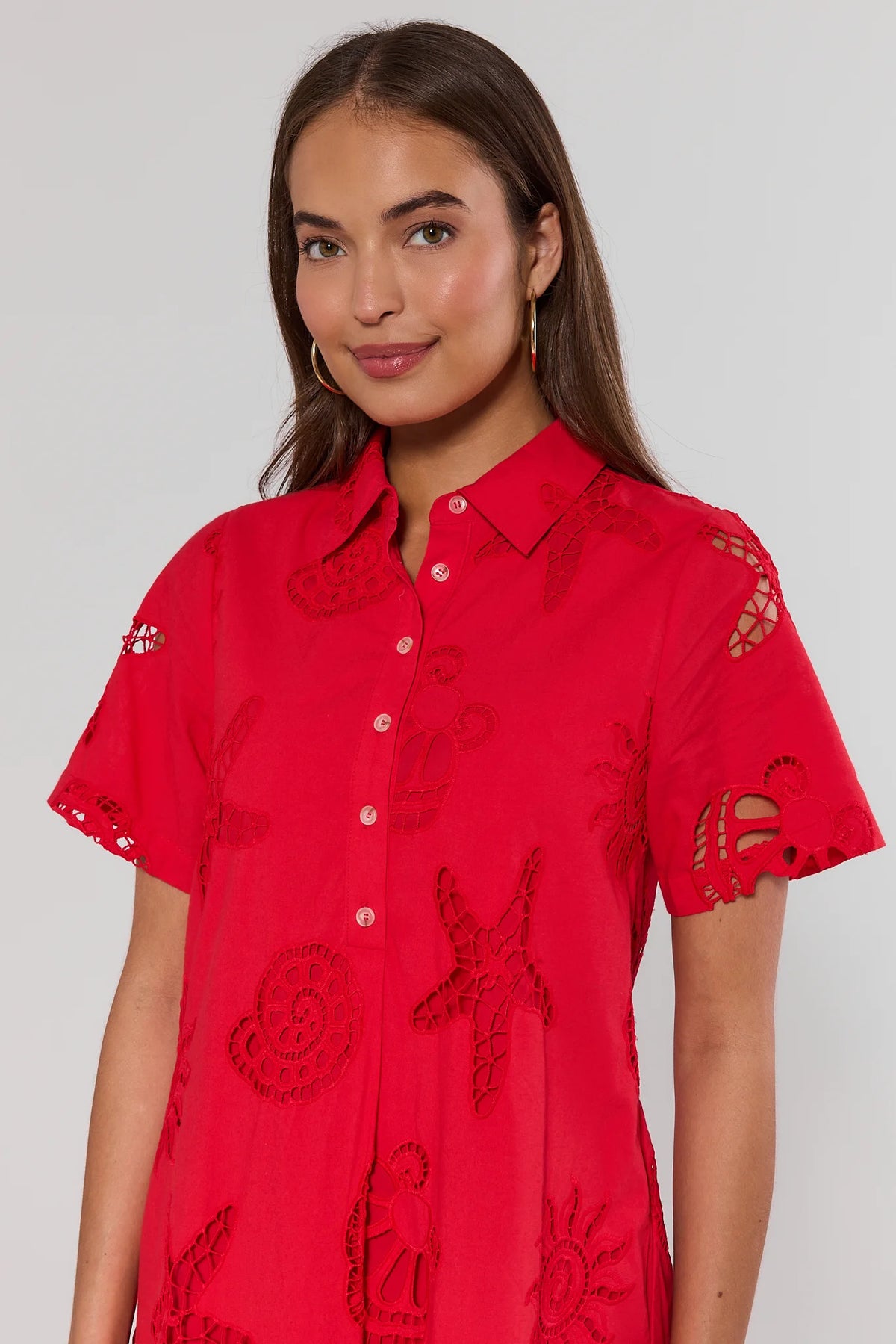 close up Woman wearing a red embroidered shirt against a plain background