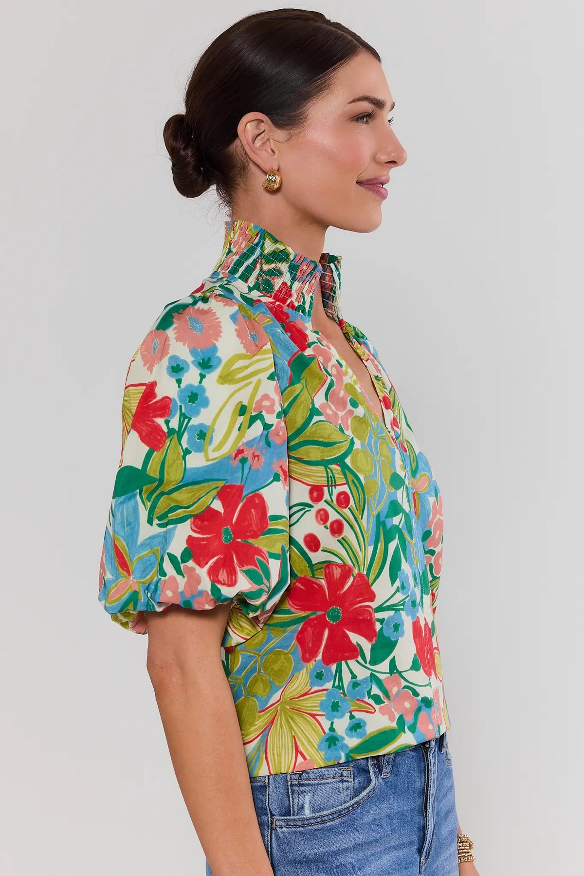 side shot Woman wearing a colorful floral blouse against a plain background