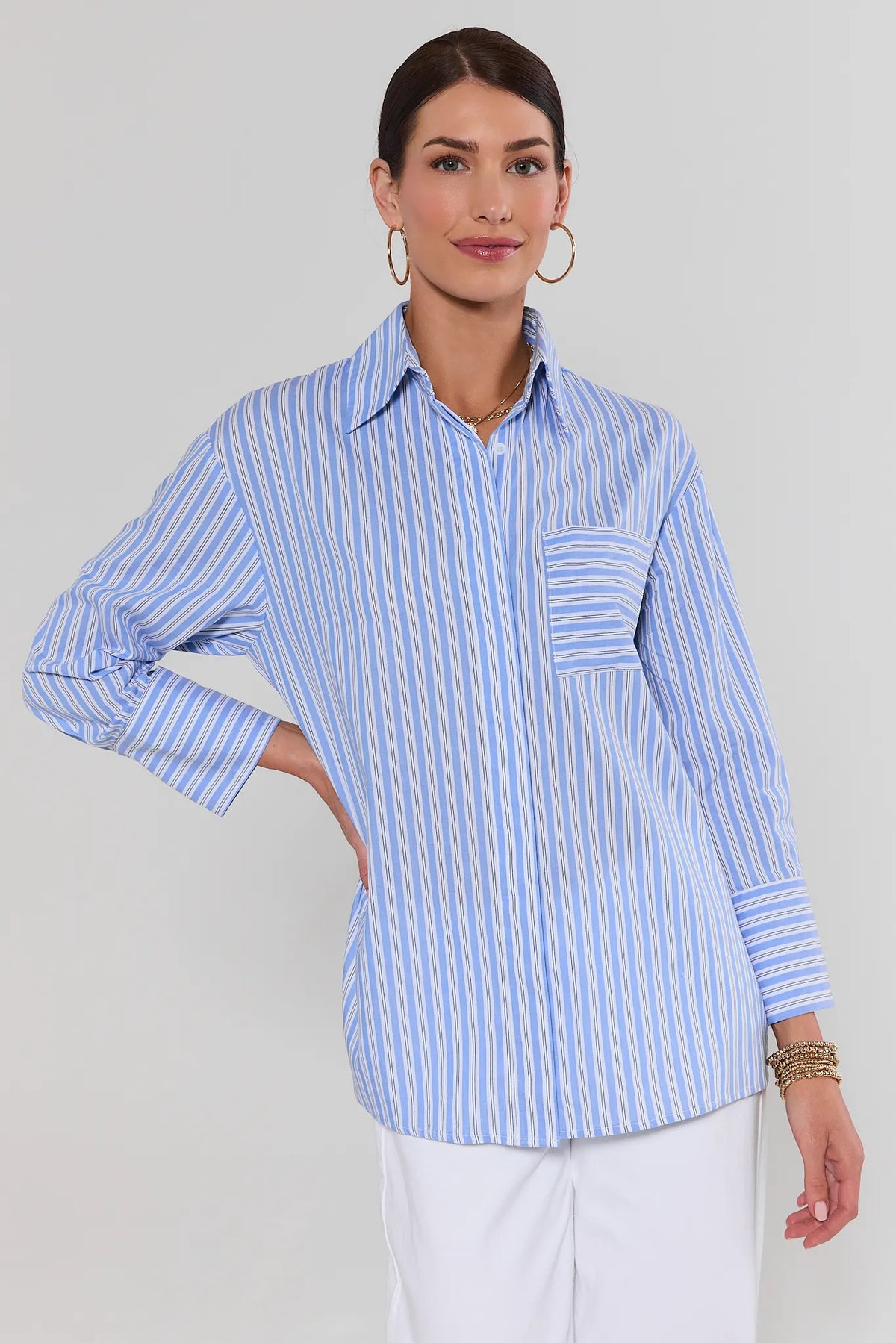 Woman wearing a light blue striped button up shirt, relaxed fit, front view | Avara