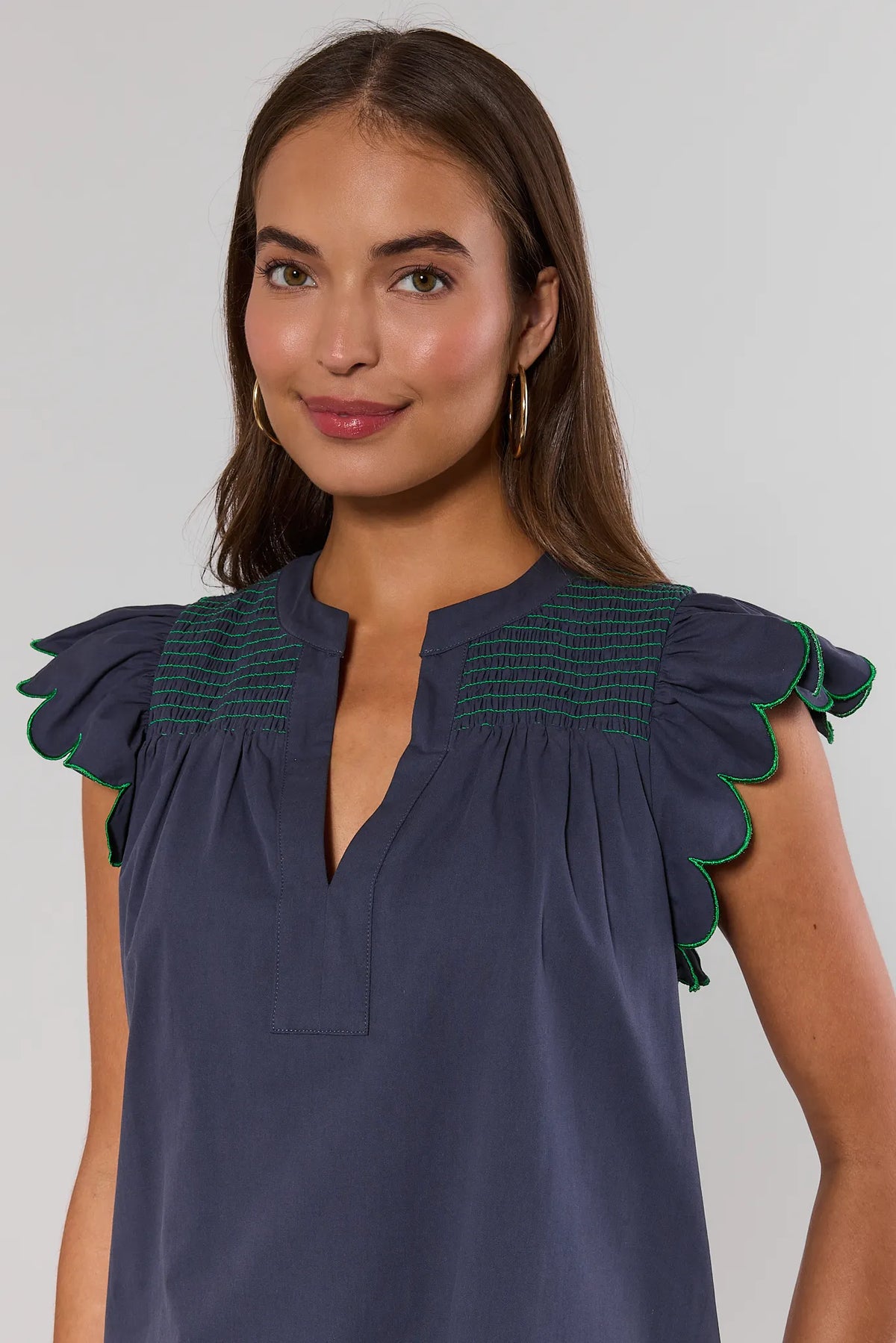 Navy scalloped flutter sleeve dress close-up showing smocked yoke and green trim detail | Avara