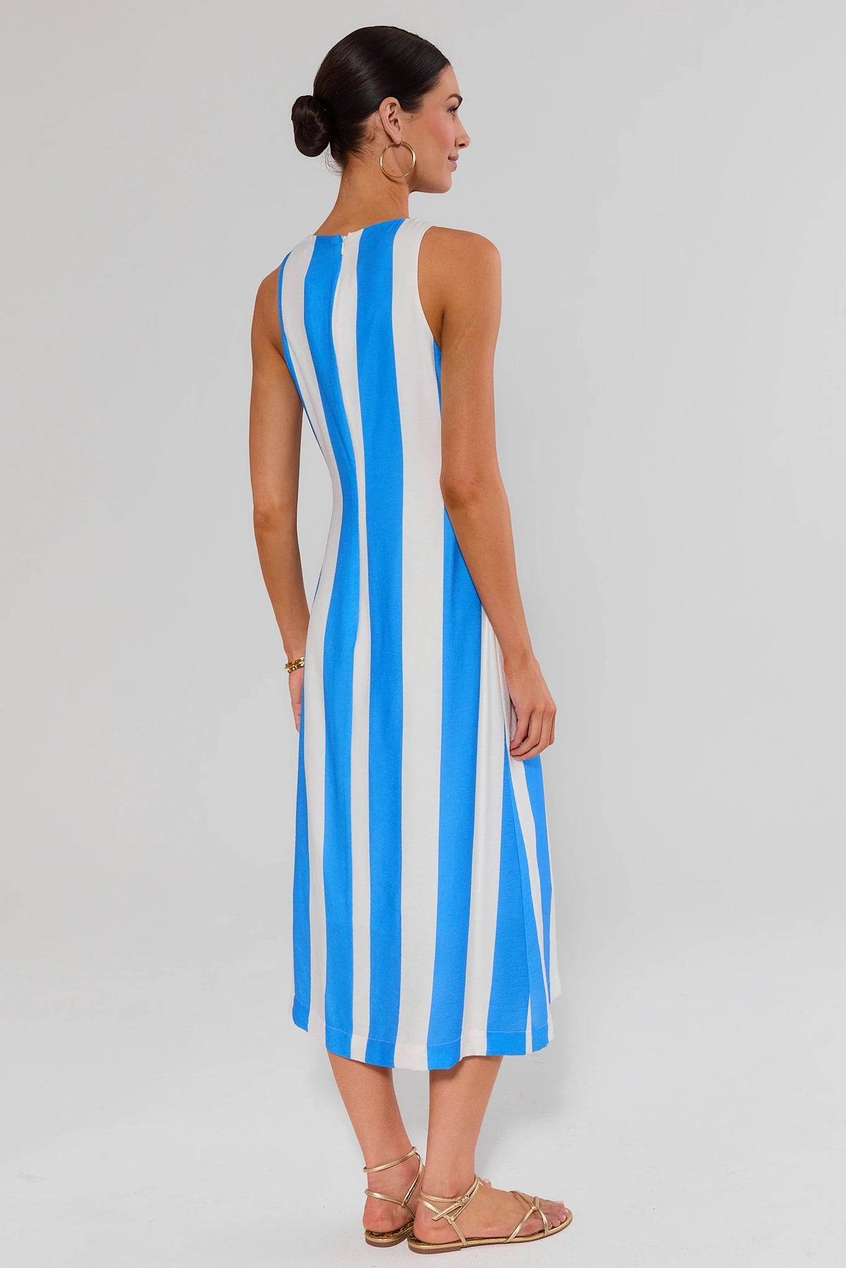 Back view of blue striped midi dress showing zip closure and flowy midi hem on model | Avara