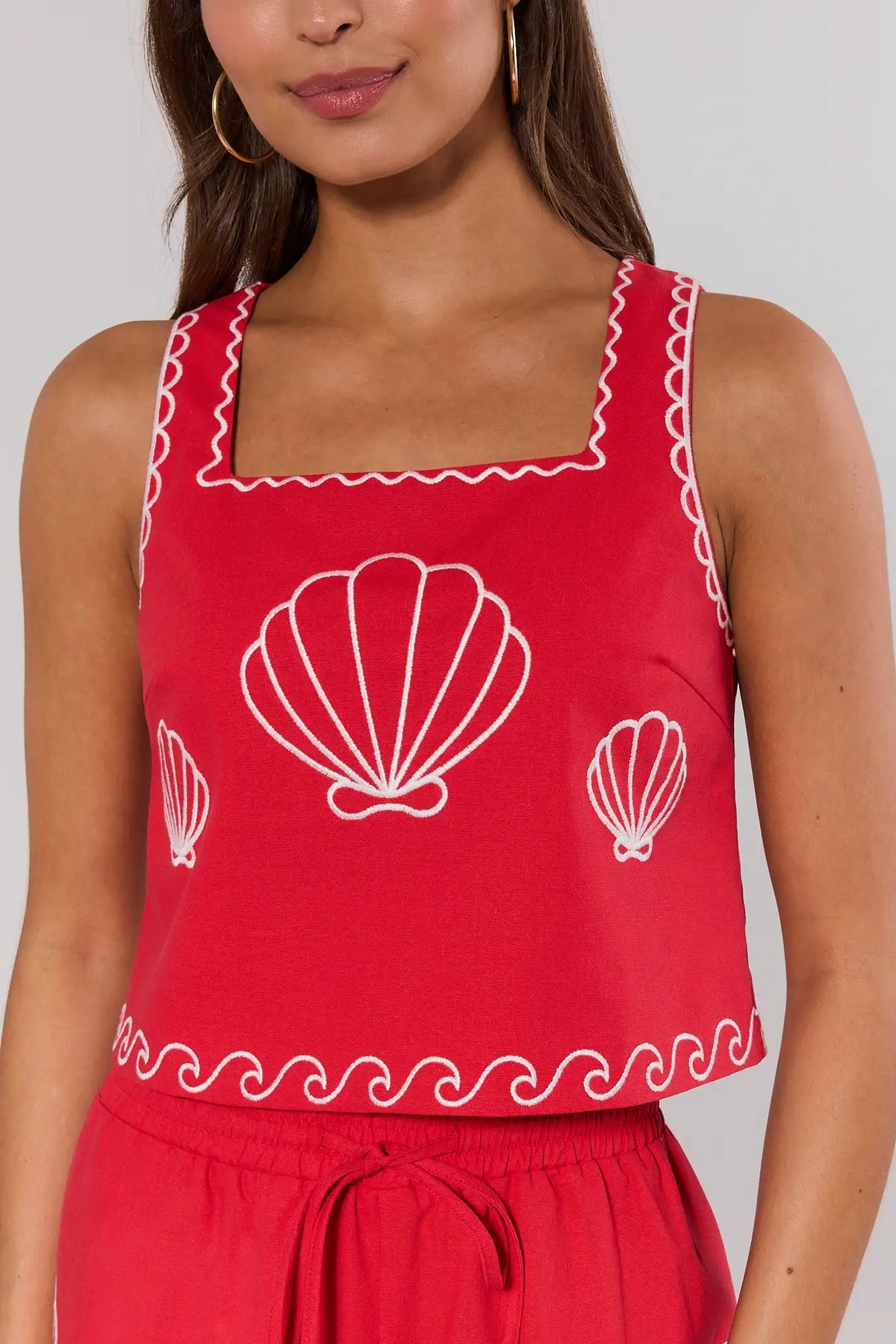 Close-up of red seashell embroidered tank top showing white shell and wave embroidery detail | Avara