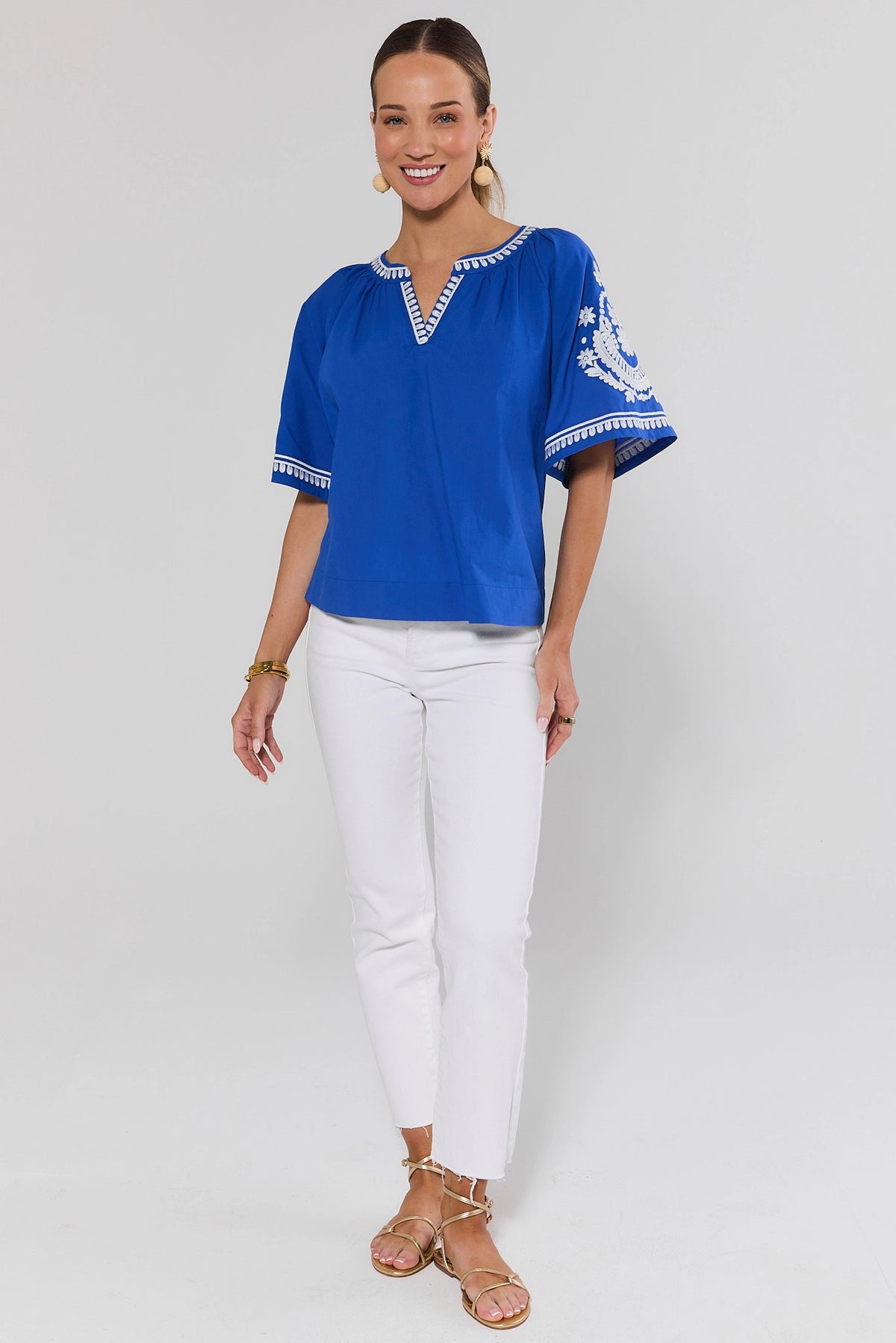 Essie Blue Embroidered Top Styled with White Jeans and Gold Sandals - Full Length Front View | Avara