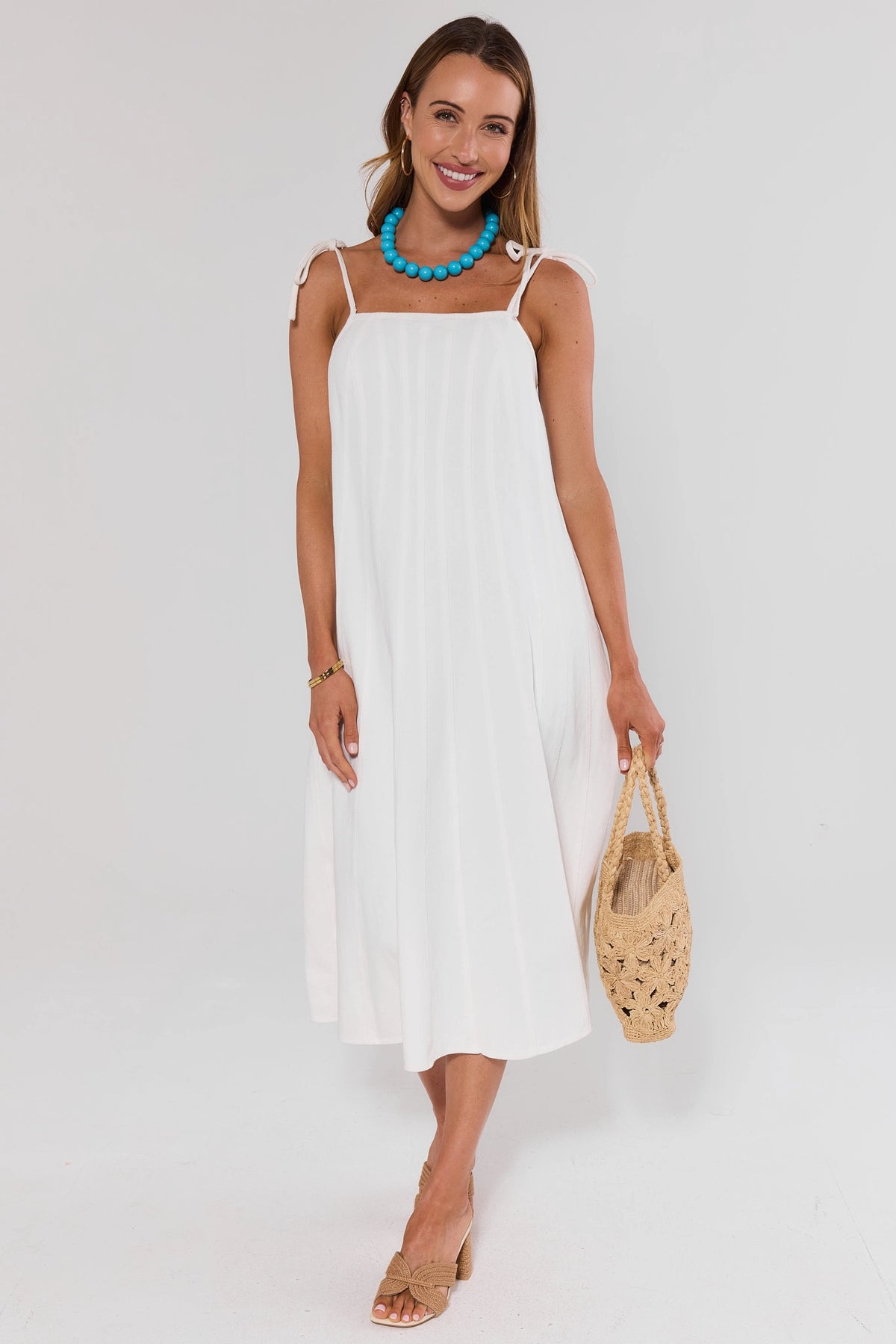 White Denim Tie Midi Dress full-length styled with woven bag and heeled sandals | Avara
