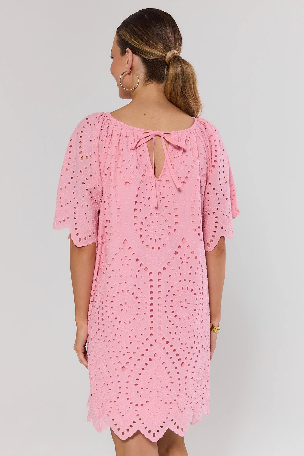 Back view of pink eyelet tunic dress showing tie back neckline detail and scalloped hem | Avara