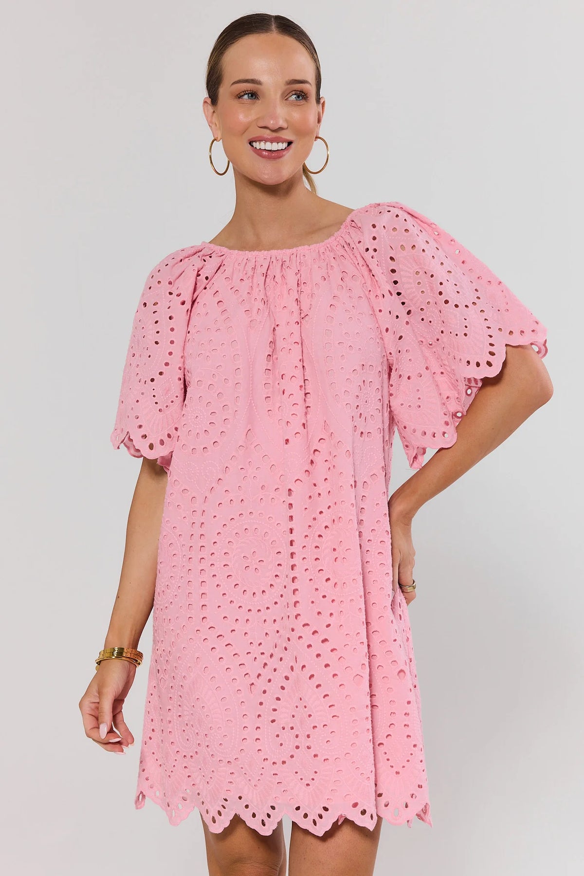 Woman wearing pink eyelet embroidered tunic dress with scalloped hem, front view on model | Avara