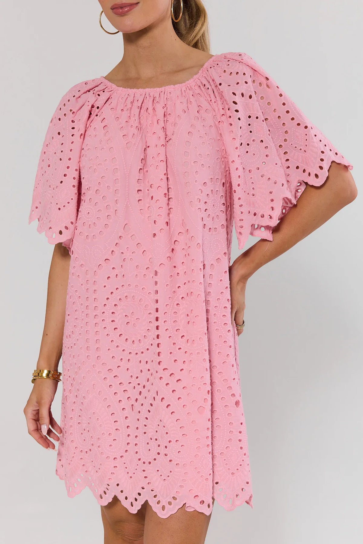 Close-up of pink eyelet tunic dress showing allover embroidered cutout pattern and scalloped sleeves | Avara