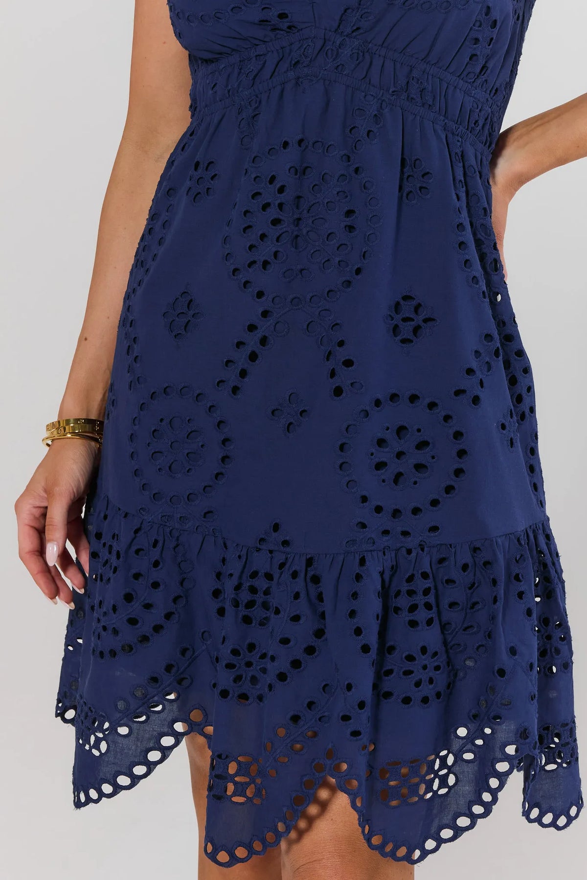 Navy blue dress with intricate cut-out pattern on a white background close up