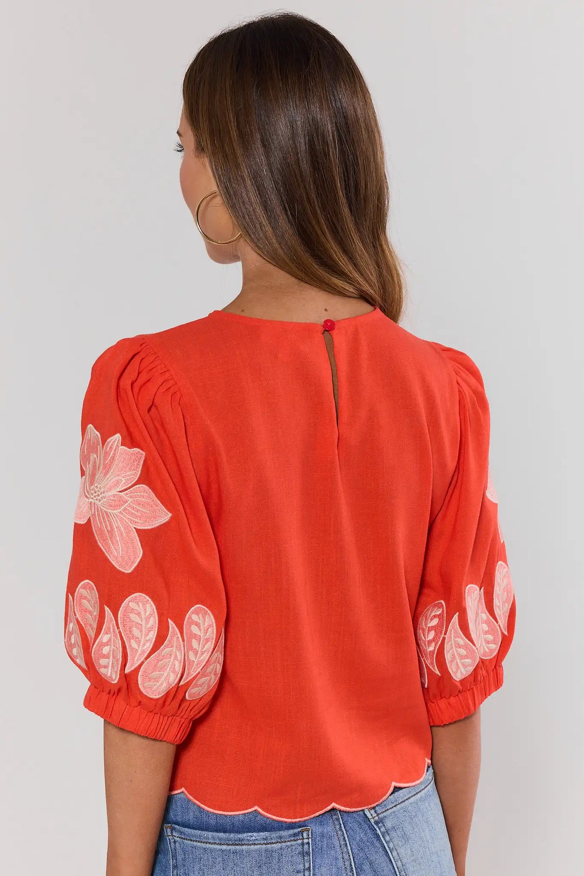 Back view of orange floral applique top by THML showing puff sleeves, keyhole closure, scallop hem | Avara