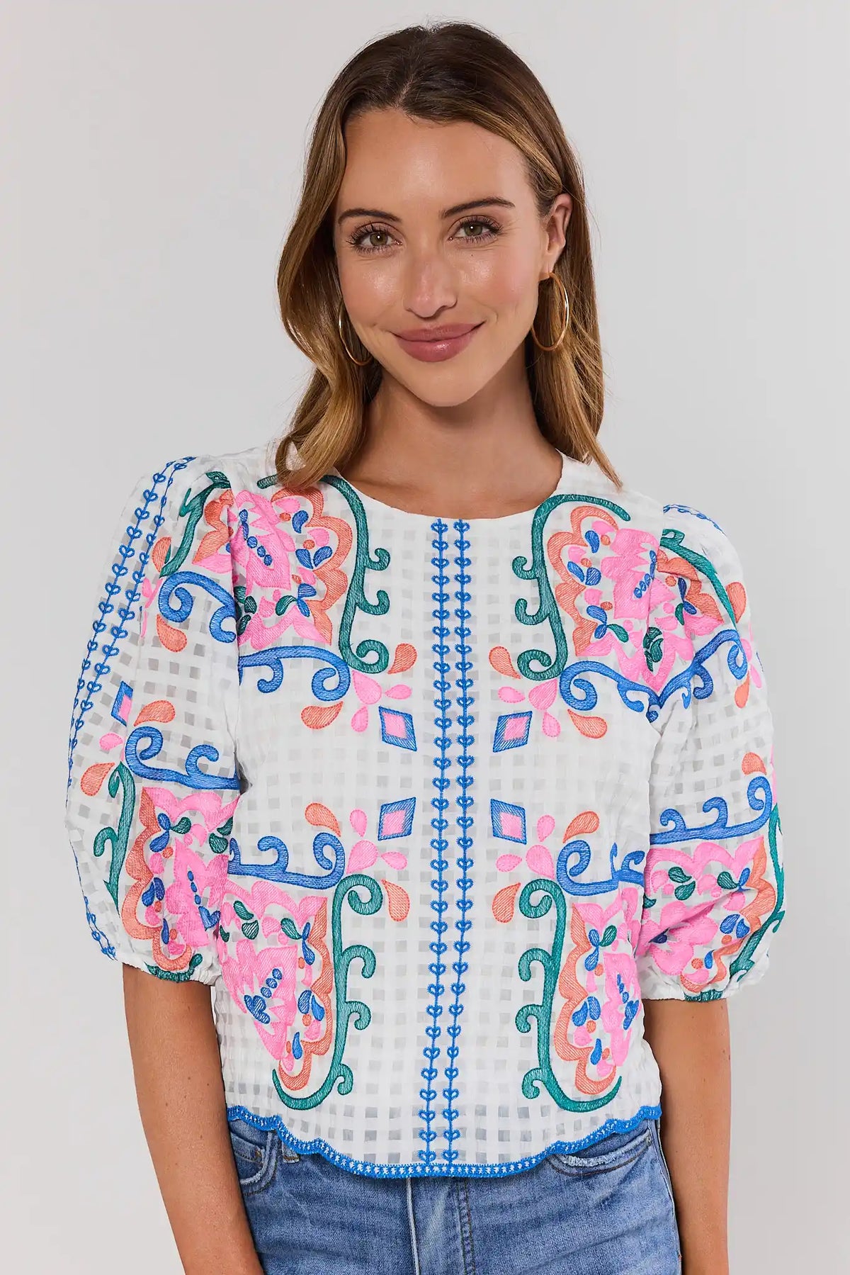 Woman wearing a colorful embroidered blouse with a plain background